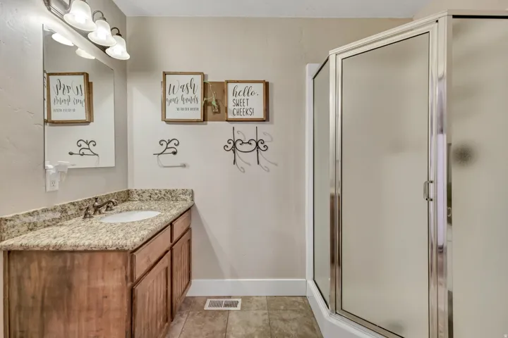 Full bath with vanity, a shower stall, and light tile patterned flooring