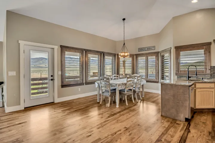 Dining area with light wood-style flooring, suspended lighting, and vaulted ceiling
