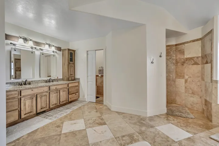 Full bath featuring double vanity, walk in shower, and vaulted ceiling