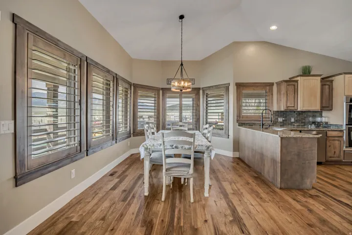 Dining room featuring dark wood-style floors, lofted ceiling, and suspended lighting