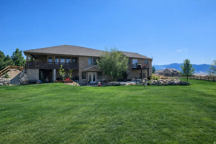 Rear view of property featuring a patio area, a balcony, and a mountain view