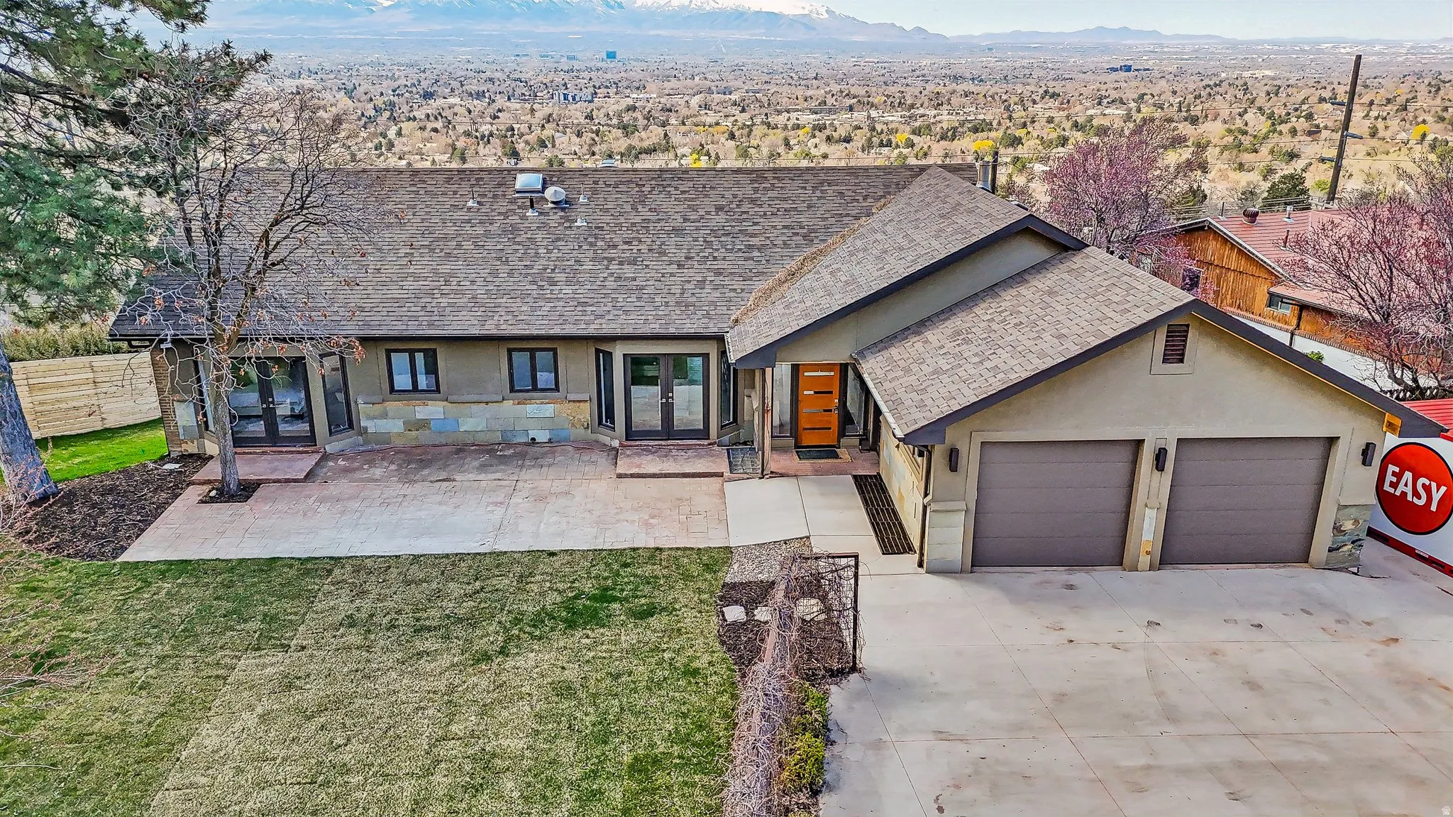 View of front facade featuring a shingled roof, french doors, stucco siding, a garage, and concrete driveway