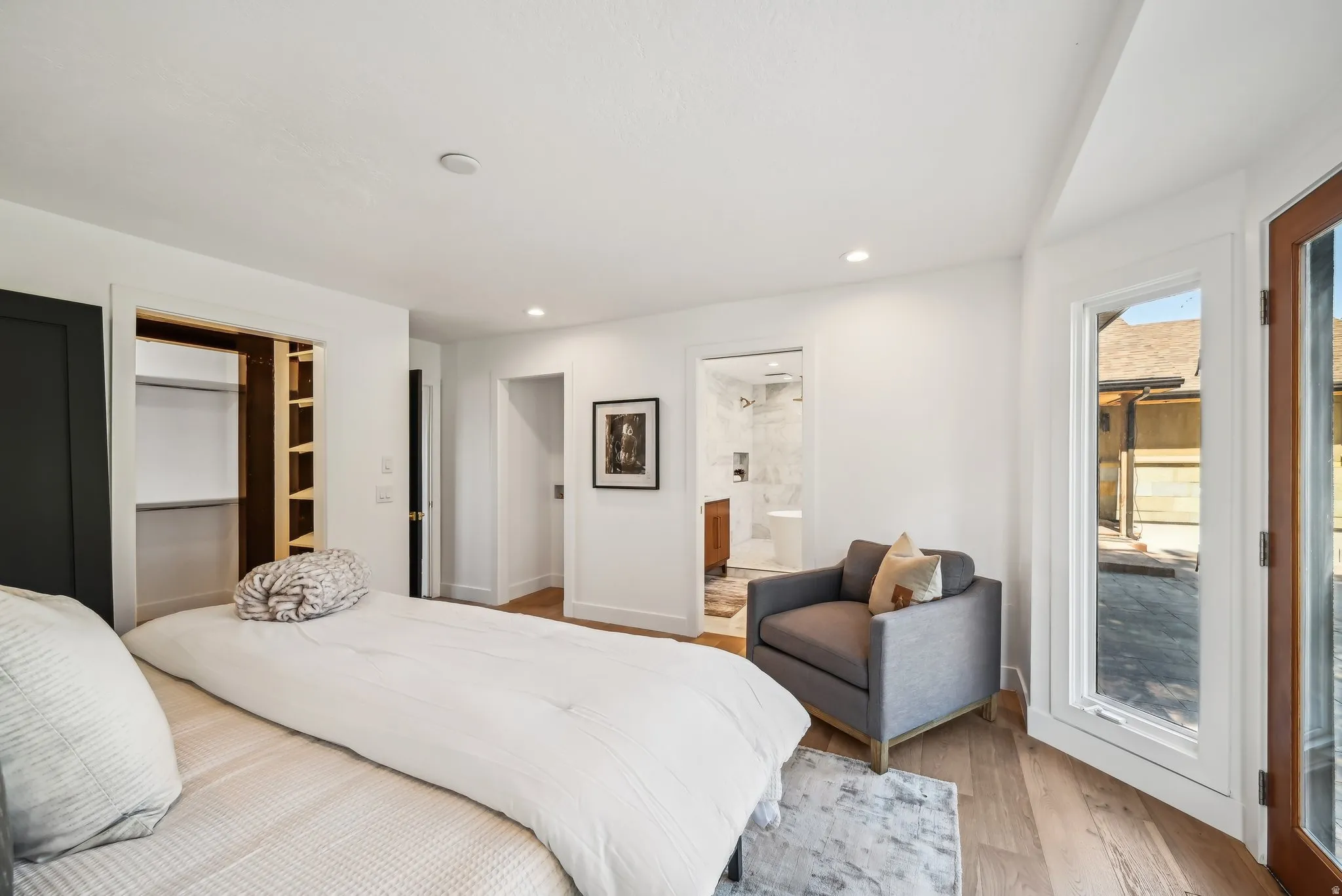 Bedroom with light wood-type flooring, a walk in closet, recessed lighting, and access to outside