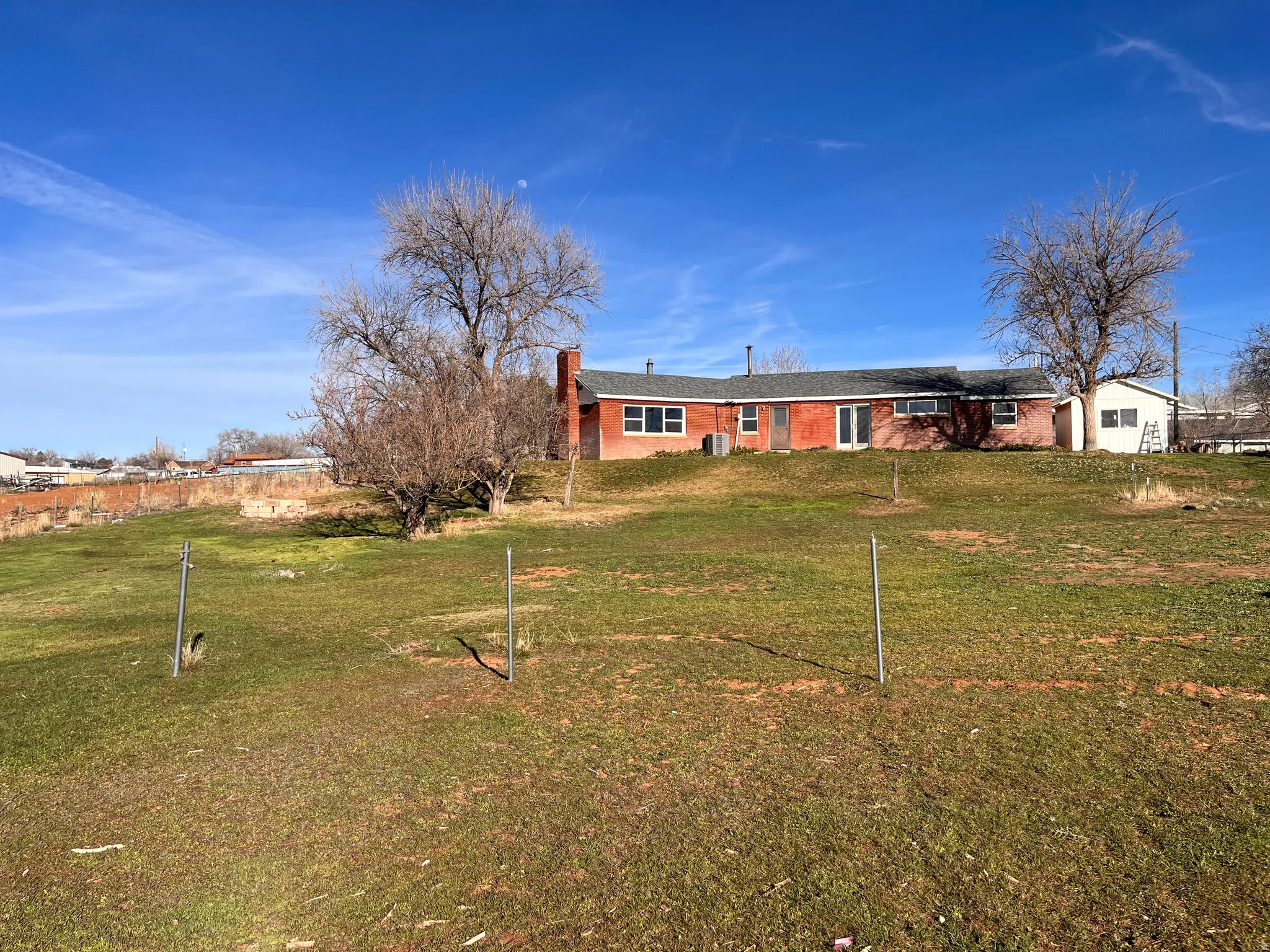 Rear view of property featuring a lawn, brick siding, and a chimney