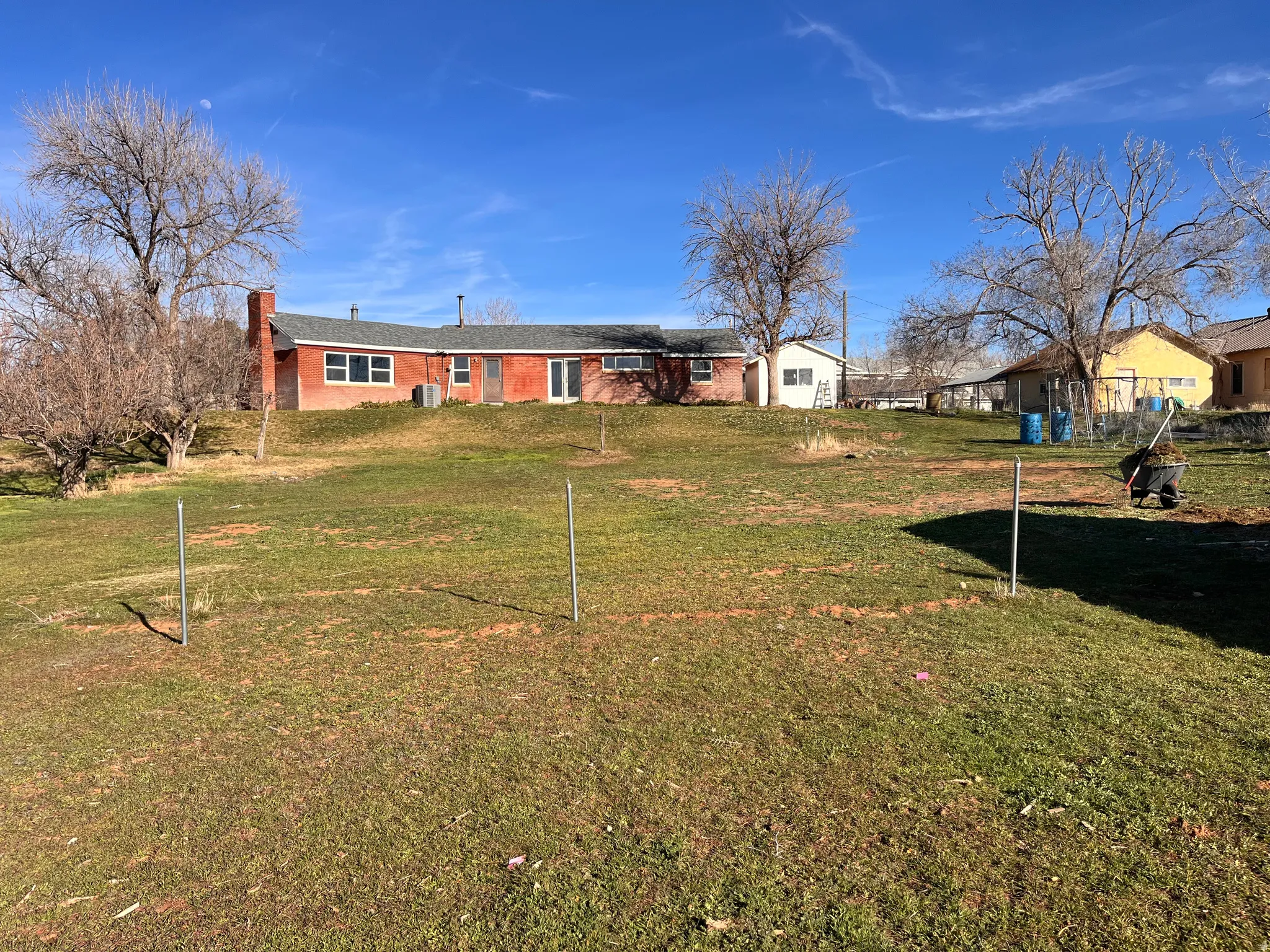 Rear view of property with a chimney, a yard, and brick siding