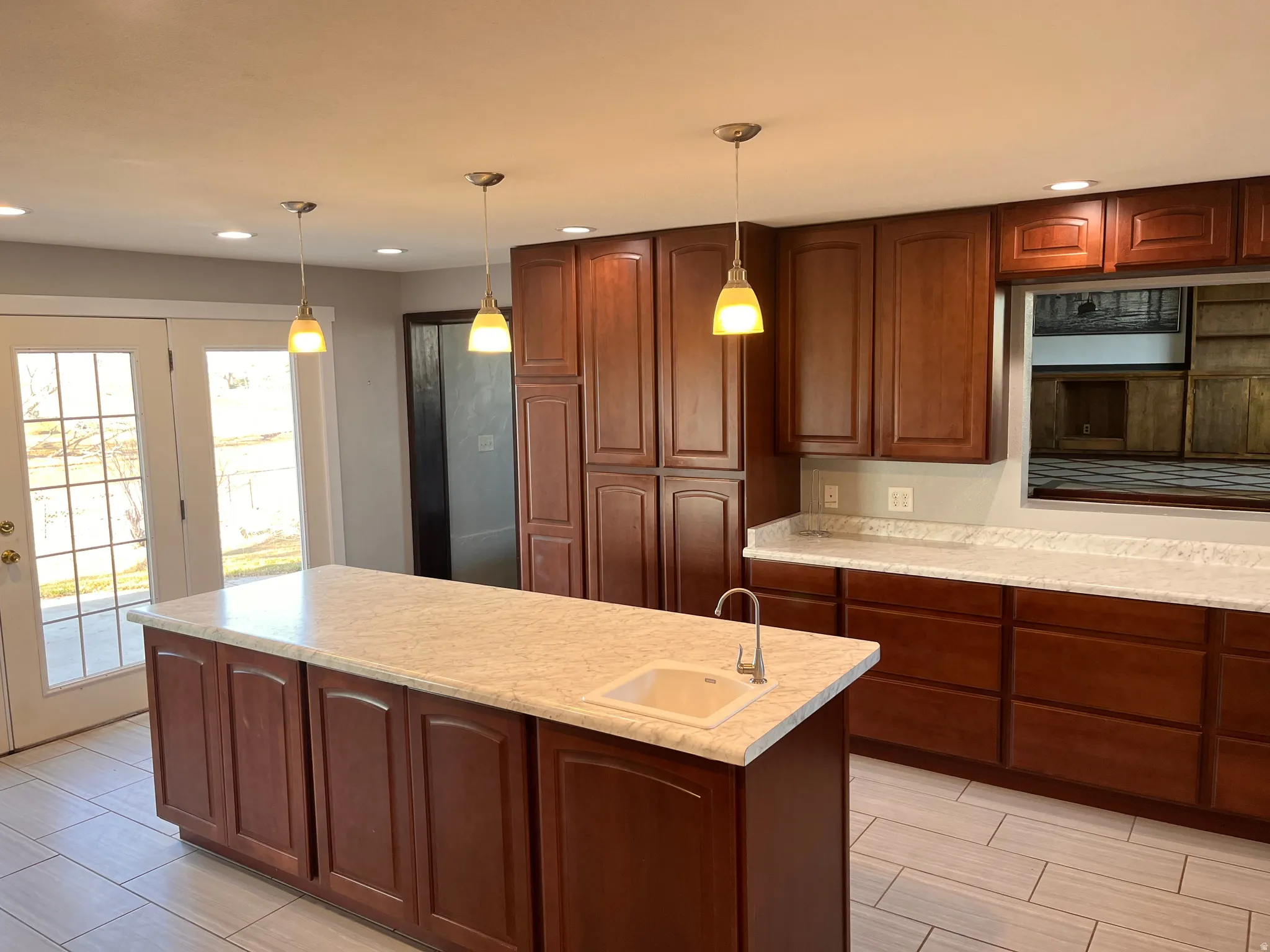 Kitchen featuring decorative light fixtures, a kitchen island with sink, wood tiled floors, and wood finish cabinetry