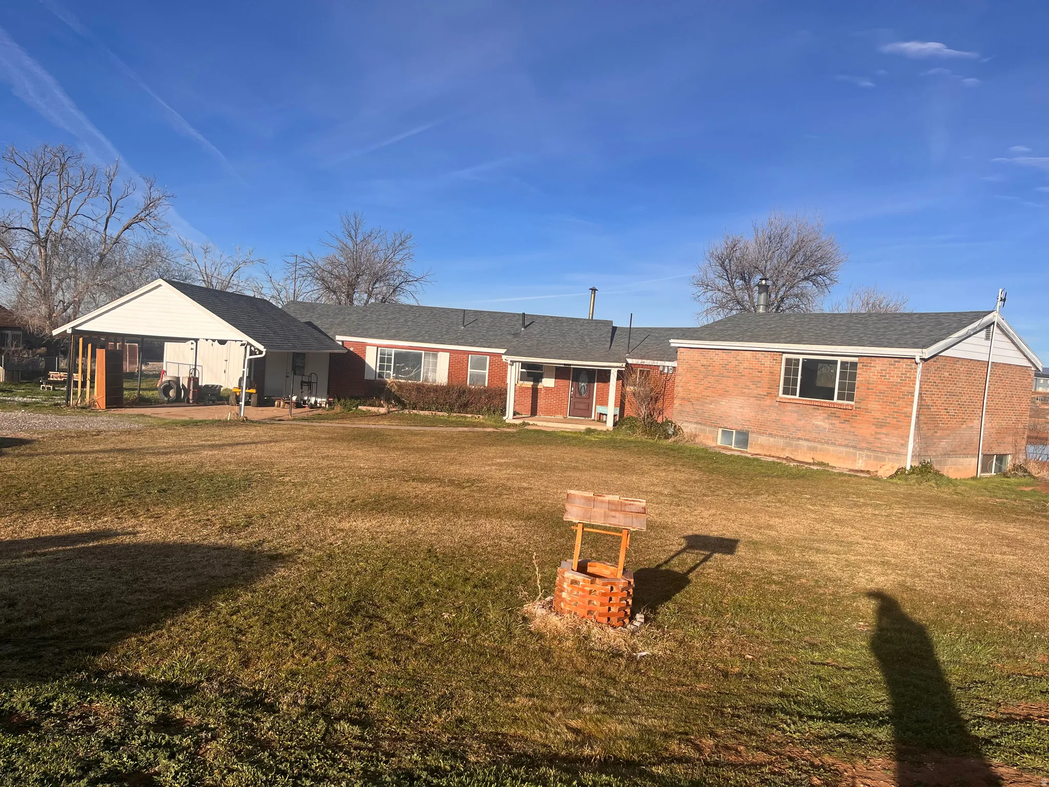 Rear view of house featuring brick siding, a yard, and a carport