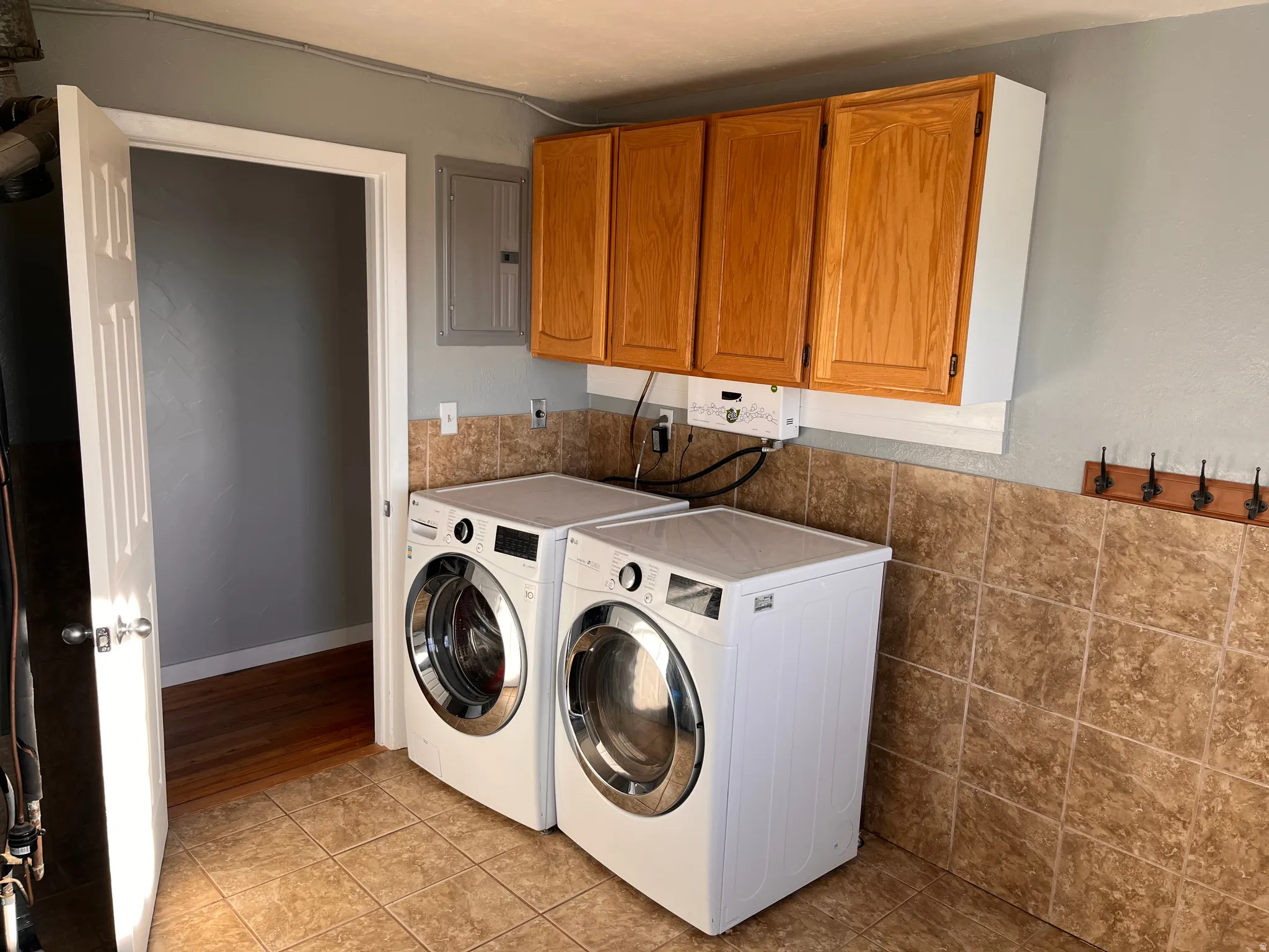 Laundry room featuring light tile patterned flooring, electric panel, cabinet space, and independent washer and dryer