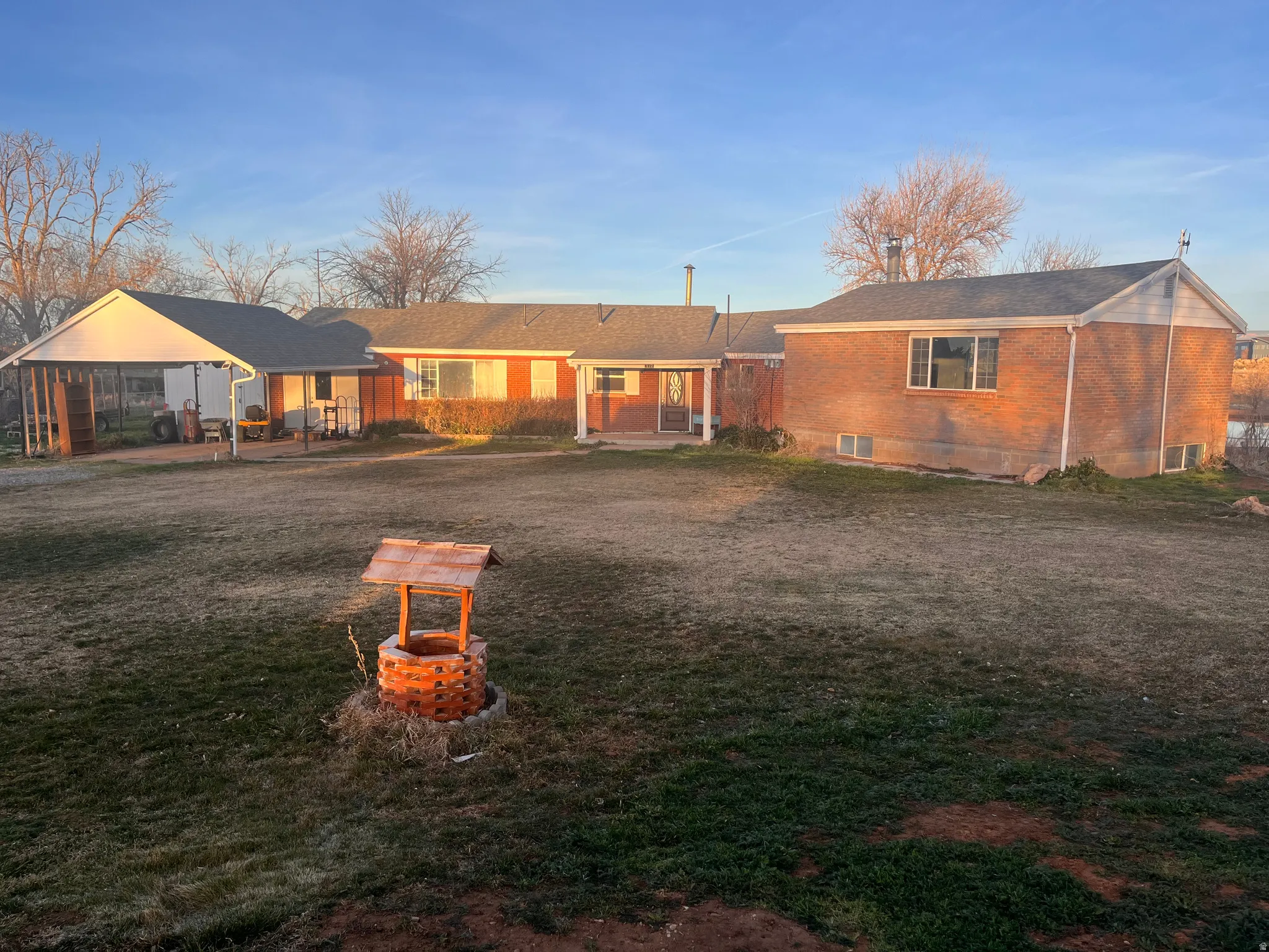 View of front of home with a patio area, brick siding, and a front lawn