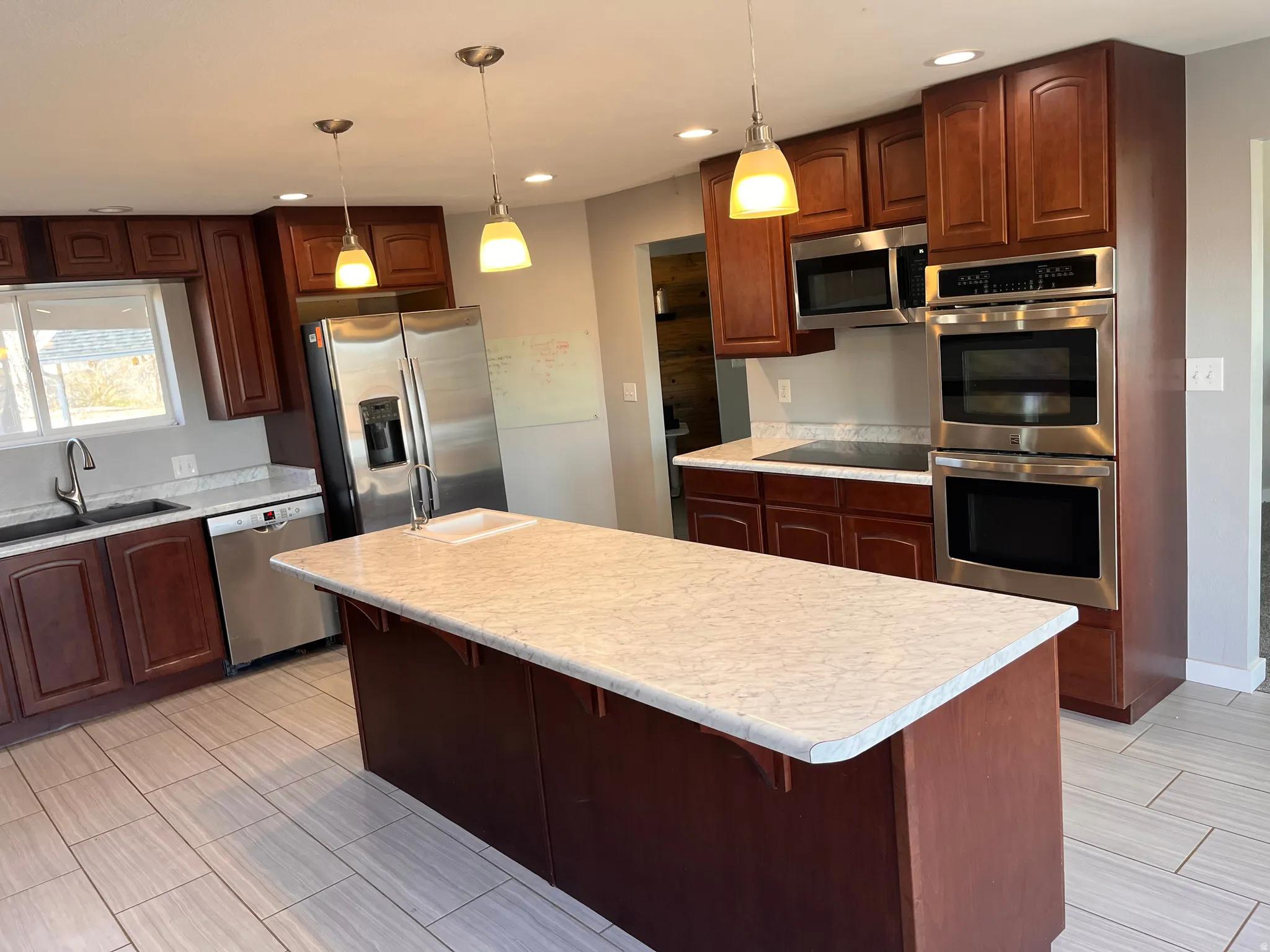 Kitchen featuring stainless steel appliances, a breakfast bar area, light countertops, a kitchen island, and decorative light fixtures