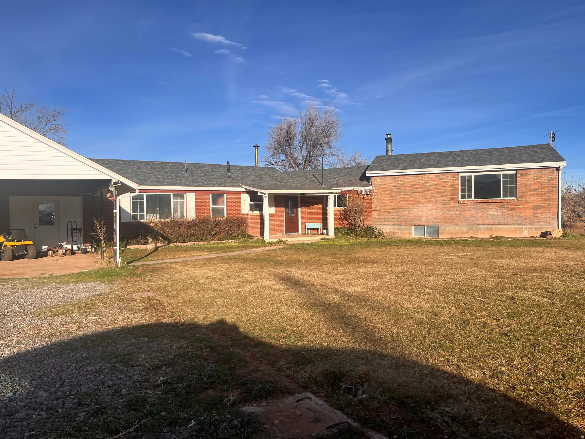 Back of house featuring brick siding, a patio, a yard, and a shingled roof