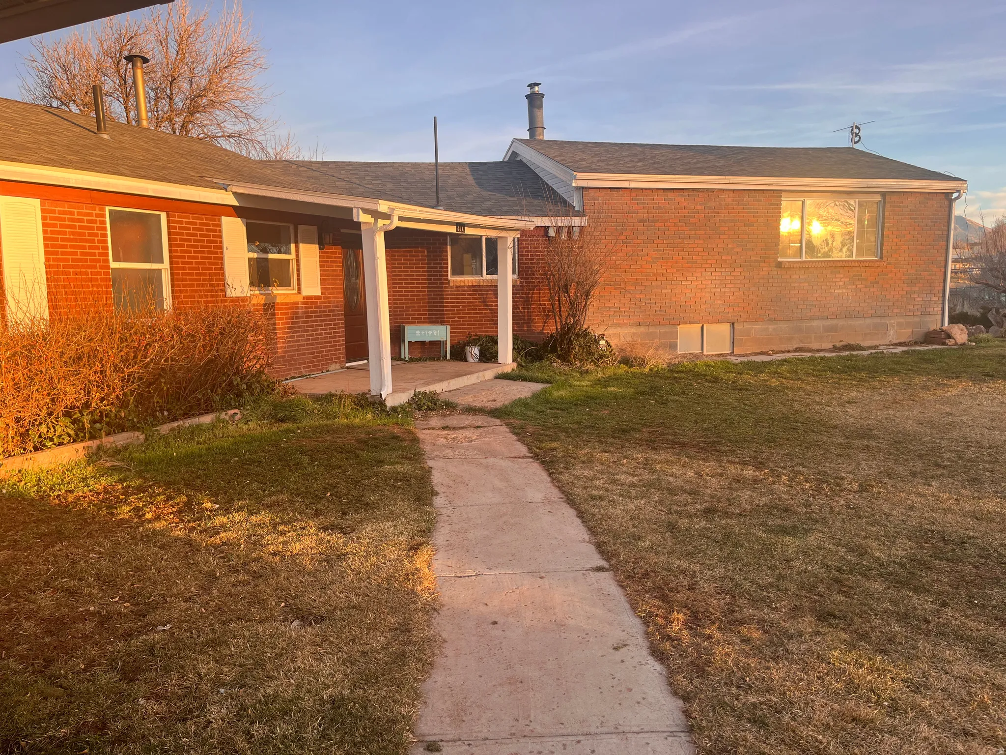 Single story home with brick siding, a front yard, and a shingled roof