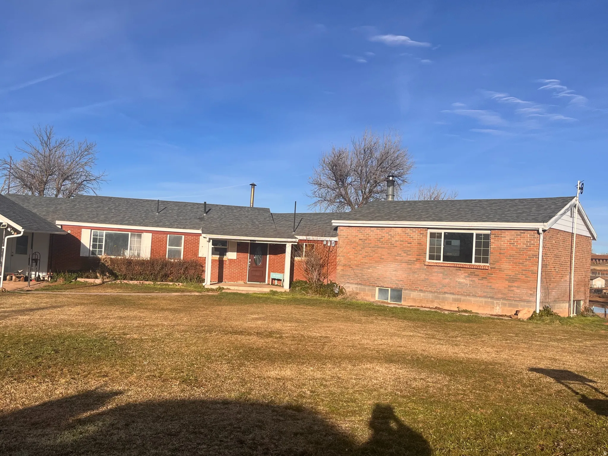 View of front of property featuring brick siding, a front lawn, and a patio