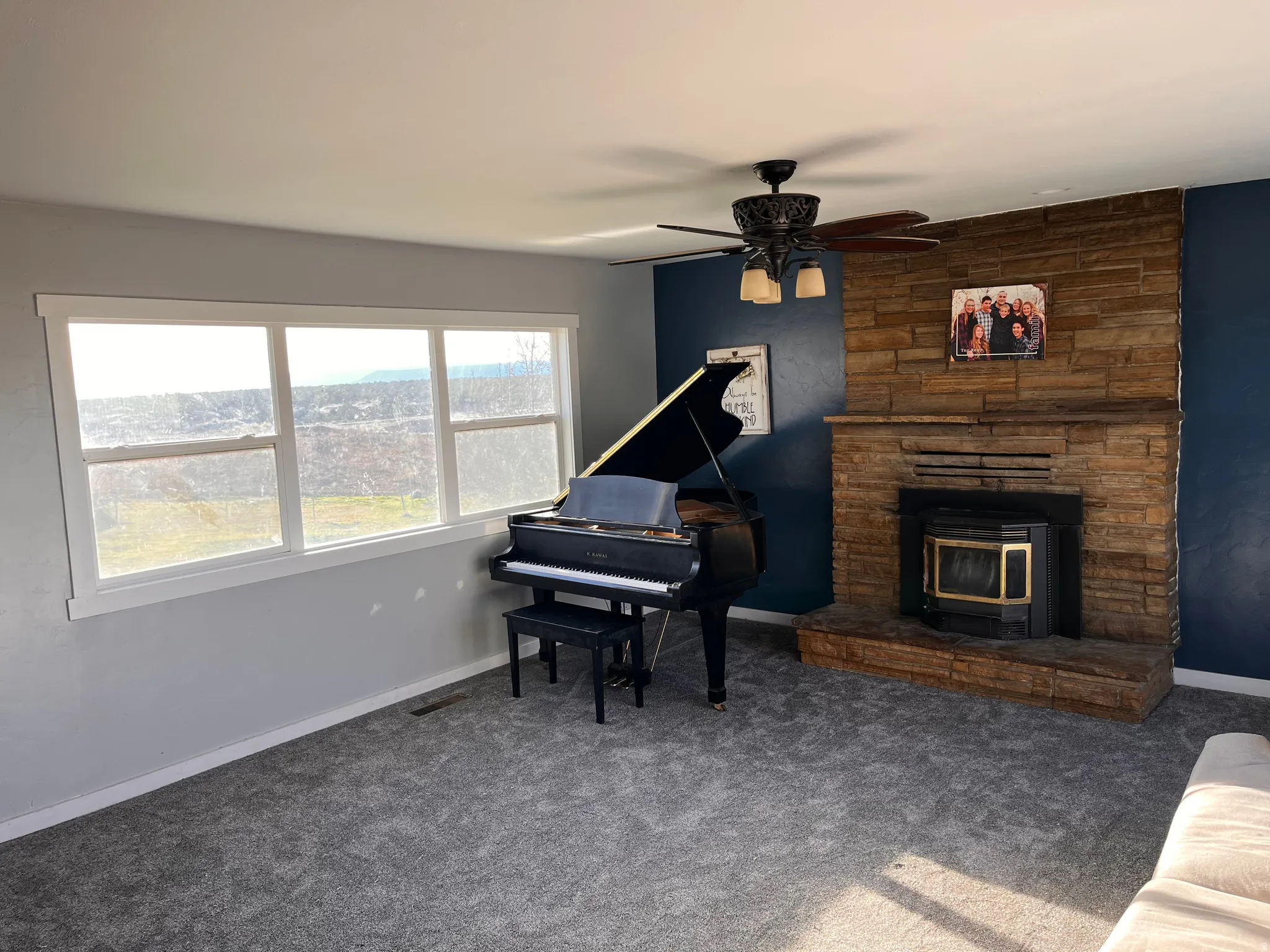 Sitting room featuring ceiling fan, a wood stove, and carpet