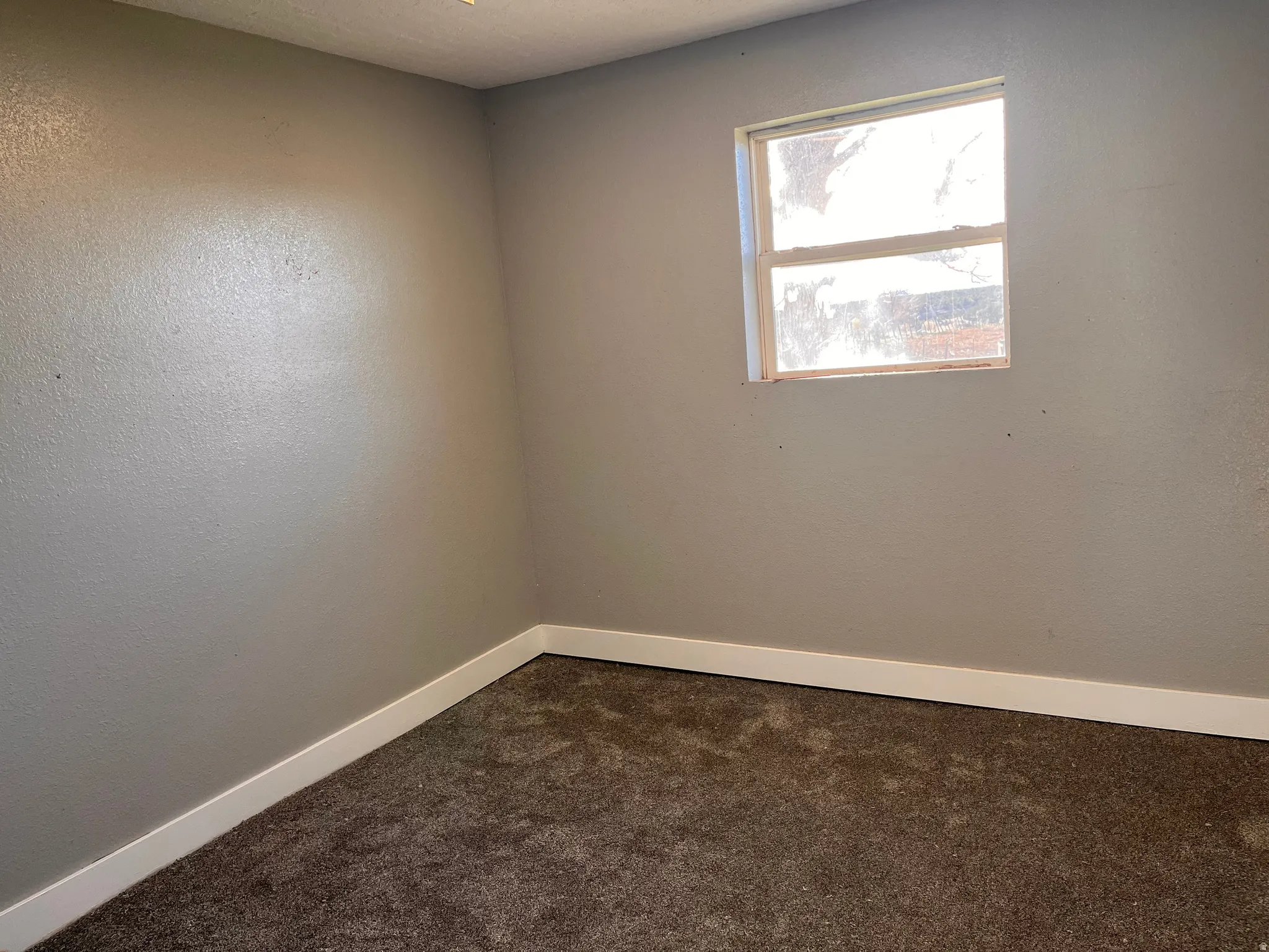 Spare room with dark colored carpet and baseboards