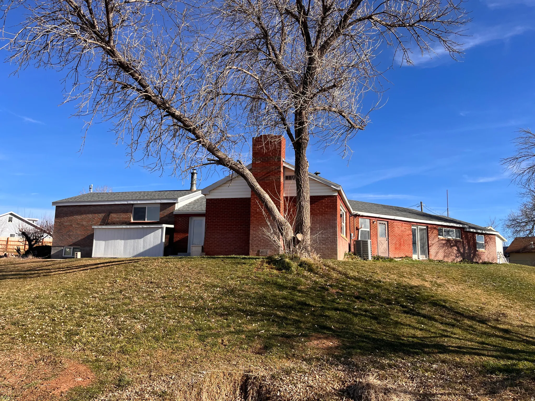Rear view of house featuring a chimney, brick siding, and a yard