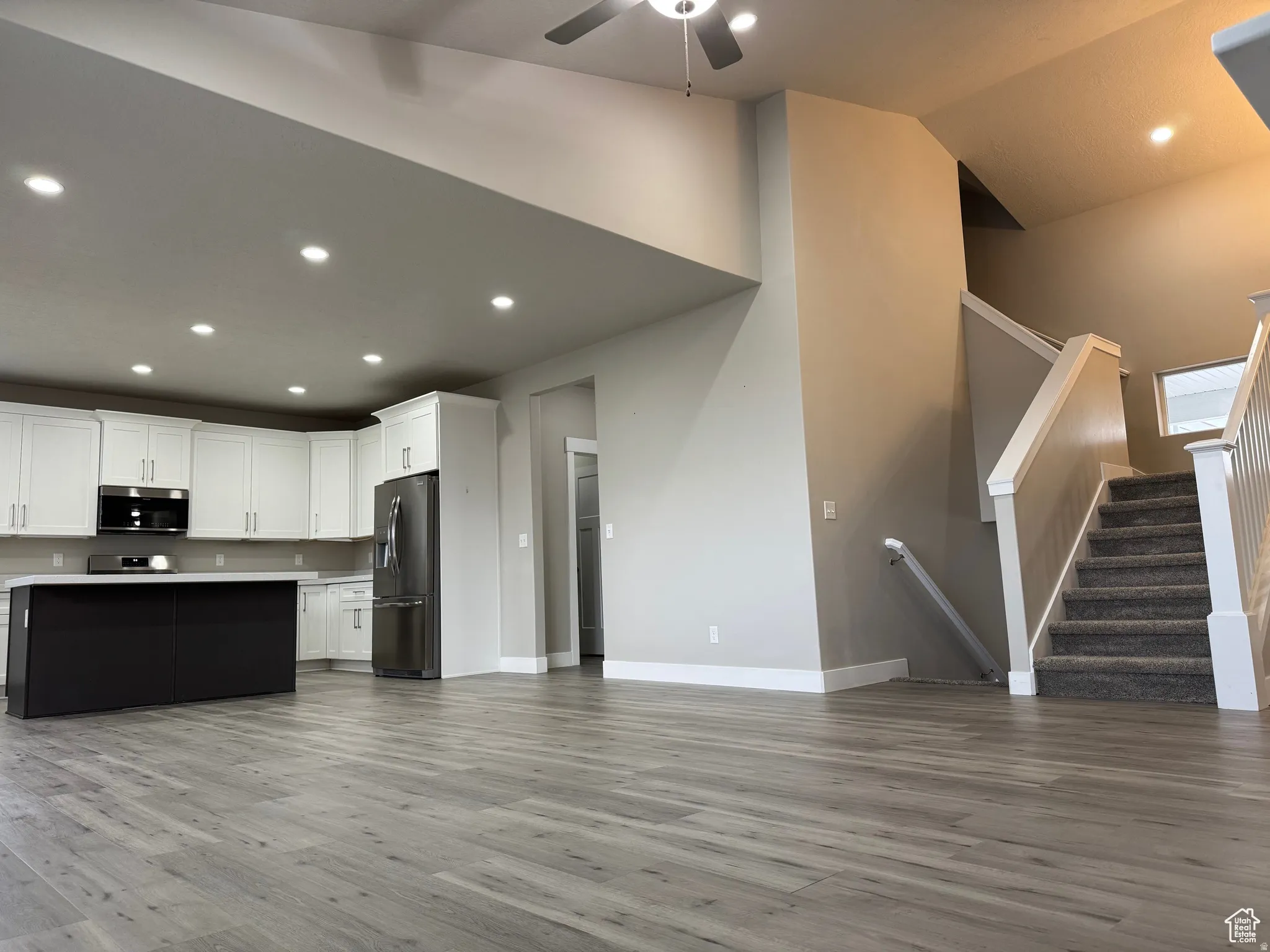 Kitchen with light countertops, recessed lighting, open floor plan, stainless steel appliances, and dark wood-type flooring
