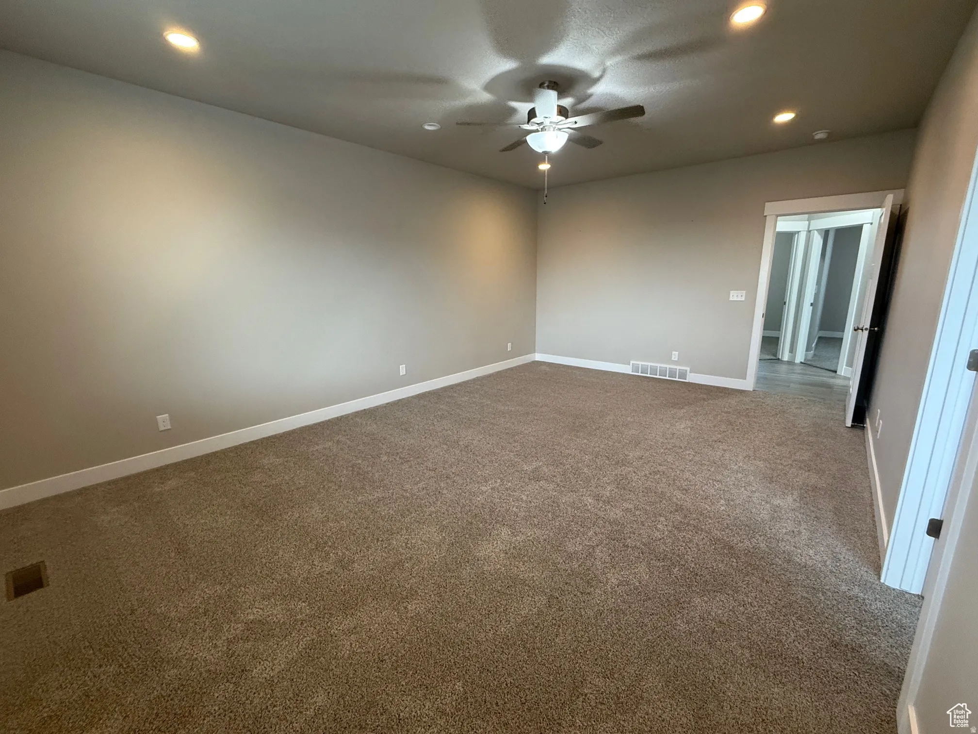 Unfurnished room with recessed lighting, a ceiling fan, and dark colored carpet