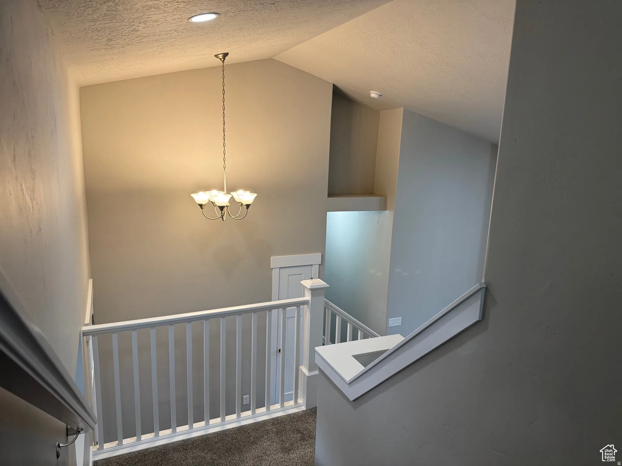 Staircase featuring a textured ceiling, carpet, and suspended lighting