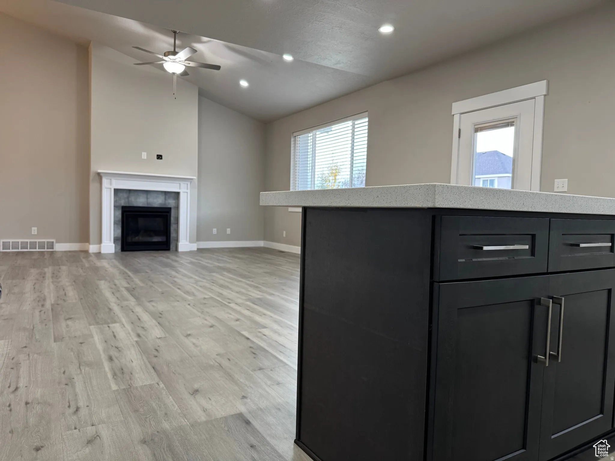 Kitchen featuring a center island, lofted ceiling, light wood-type flooring, dark cabinets, and recessed lighting