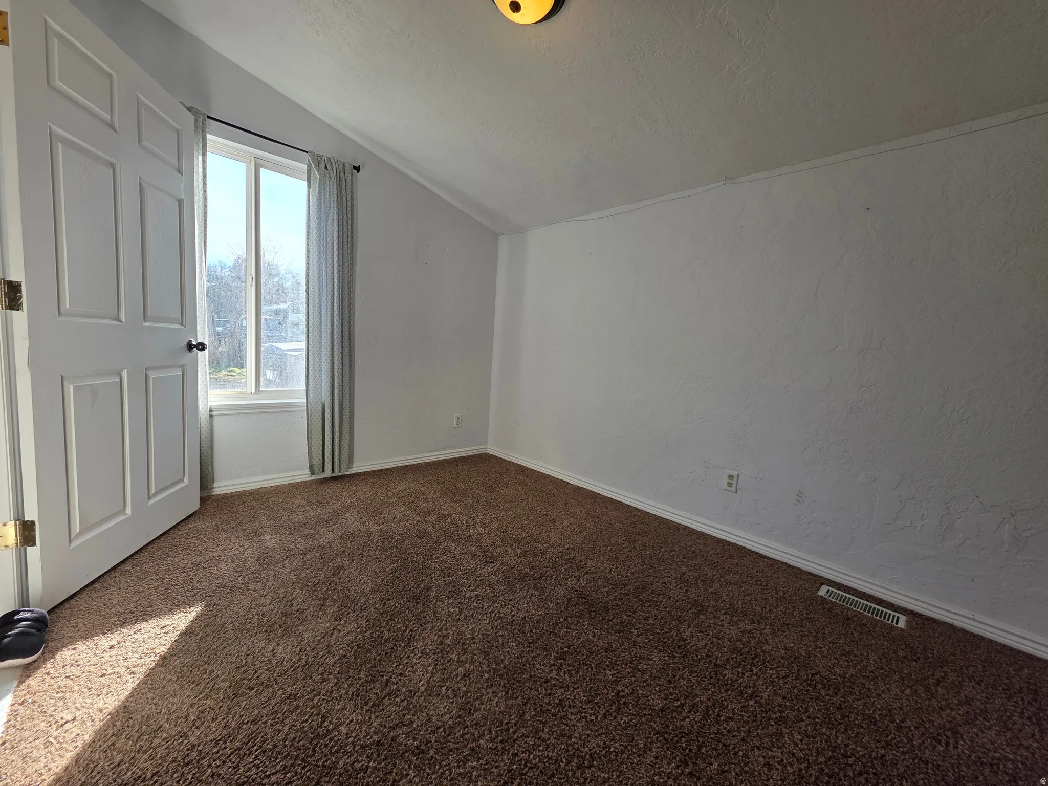 Bonus room with a textured wall and dark colored carpet