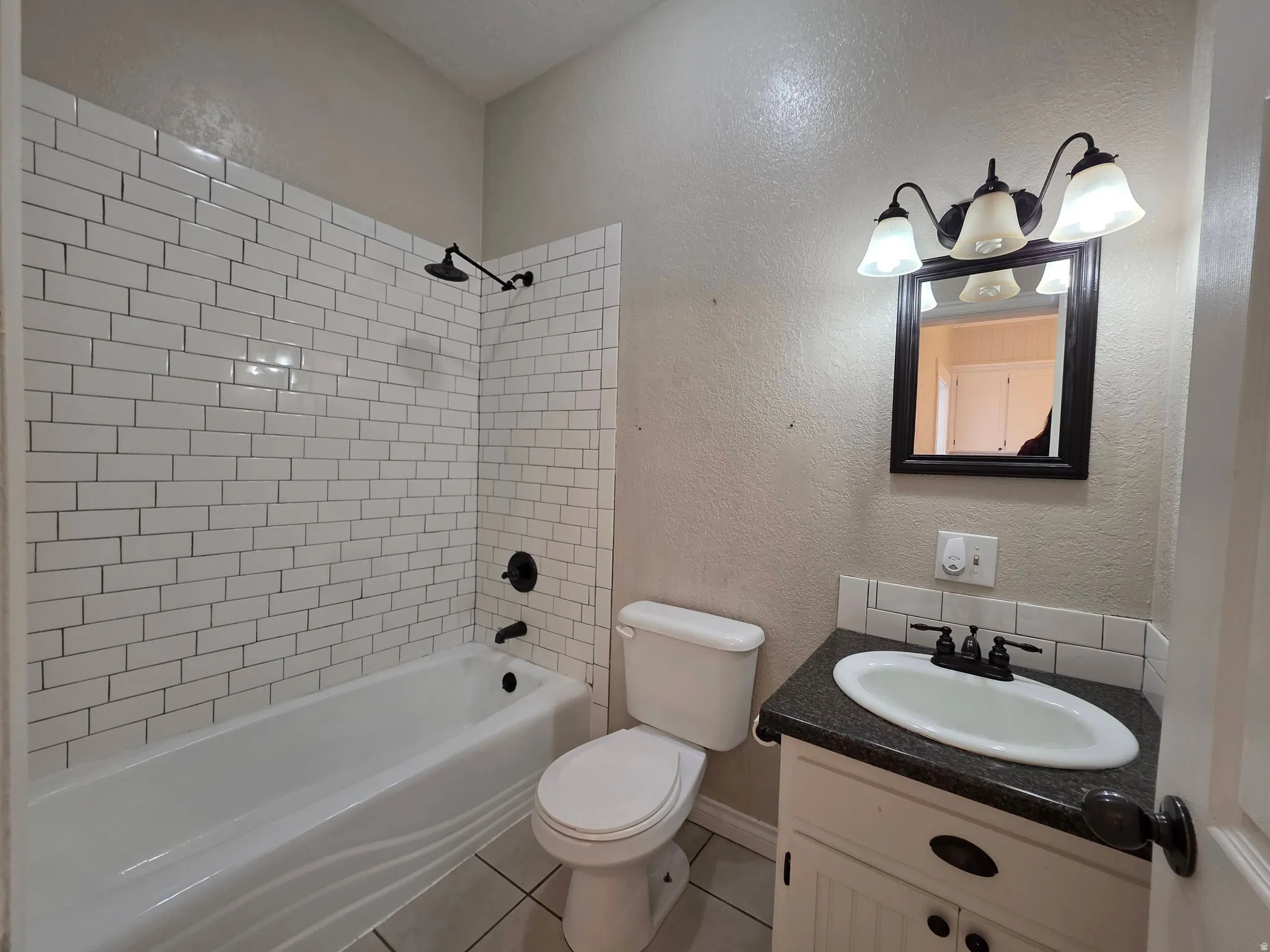 Full bath with a textured wall, vanity, shower / bath combination, and light tile patterned floors