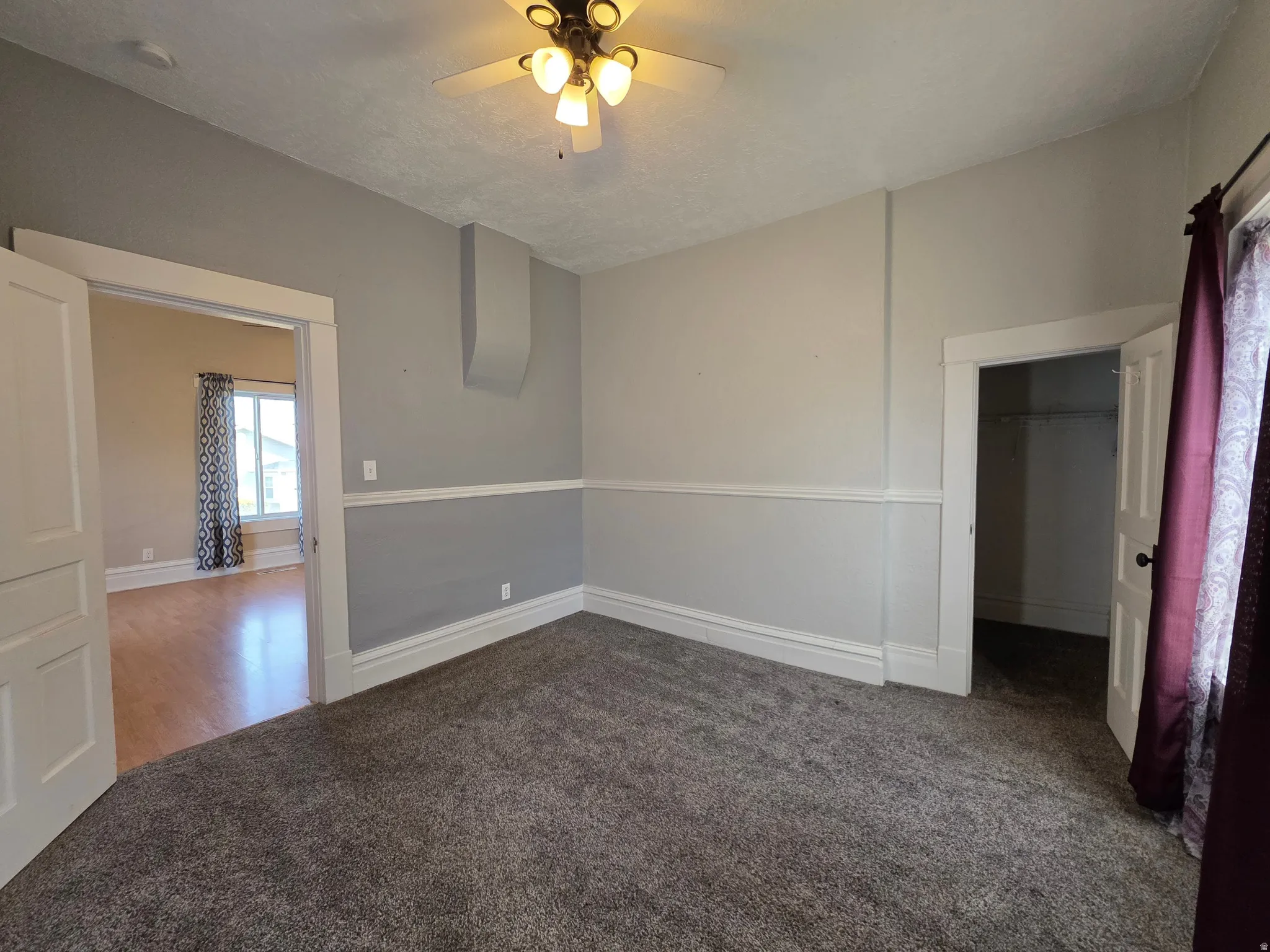 Unfurnished bedroom with carpet flooring, a walk in closet, and a ceiling fan
