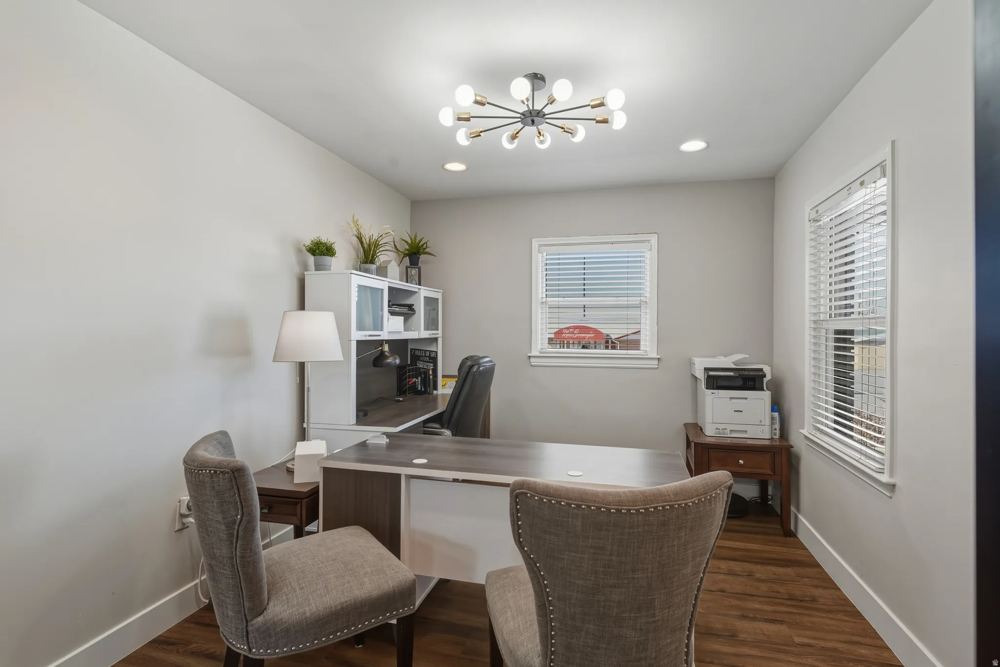 Office space featuring dark wood-style flooring and suspended lighting