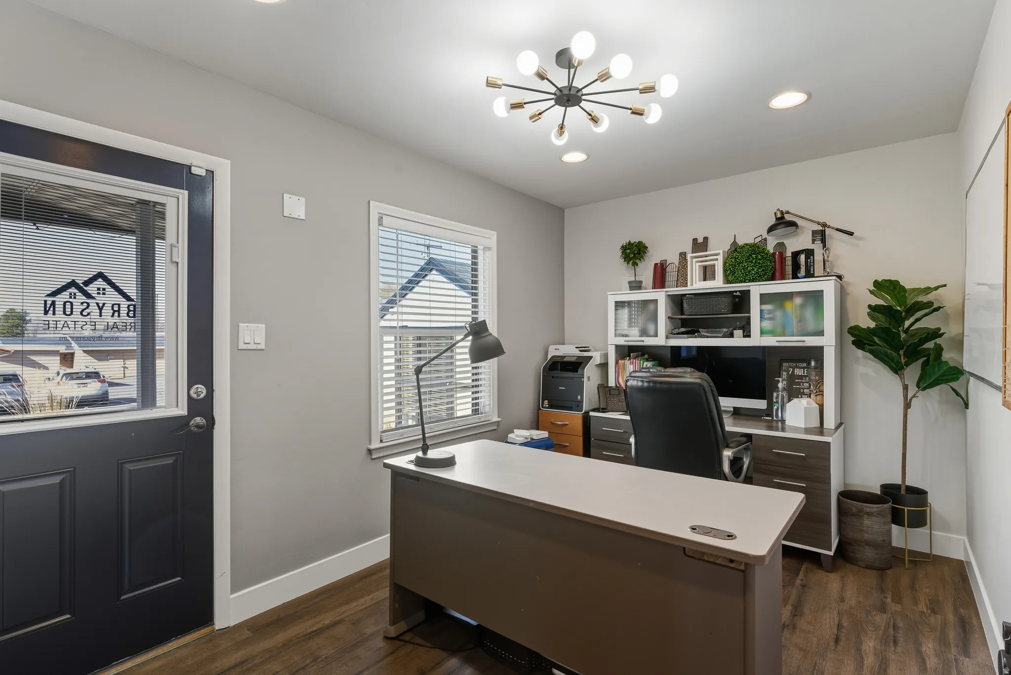 Office area featuring dark wood-style floors and suspended lighting