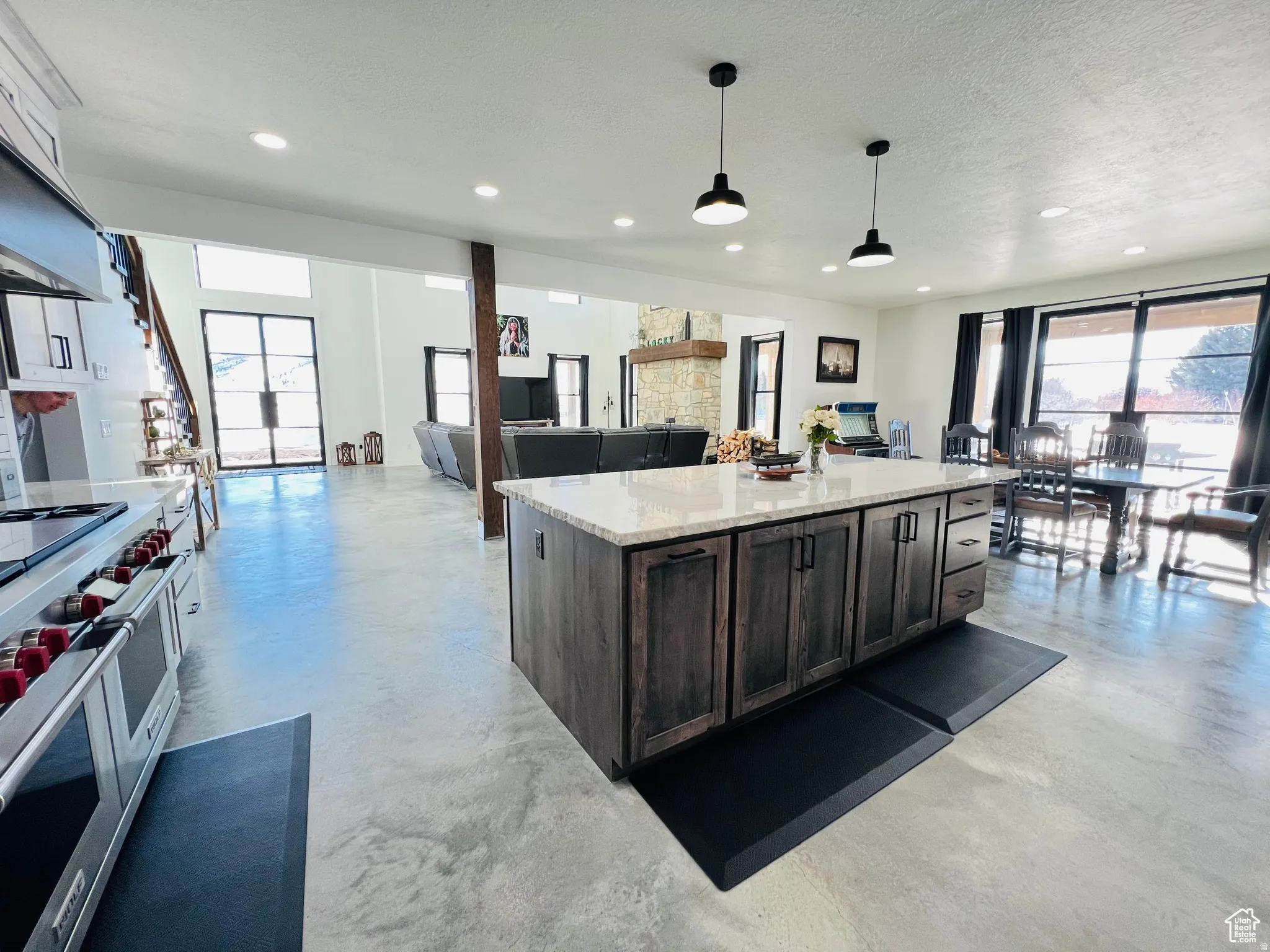 Kitchen featuring open floor plan, a kitchen island, light stone countertops, finished concrete flooring, and a textured ceiling