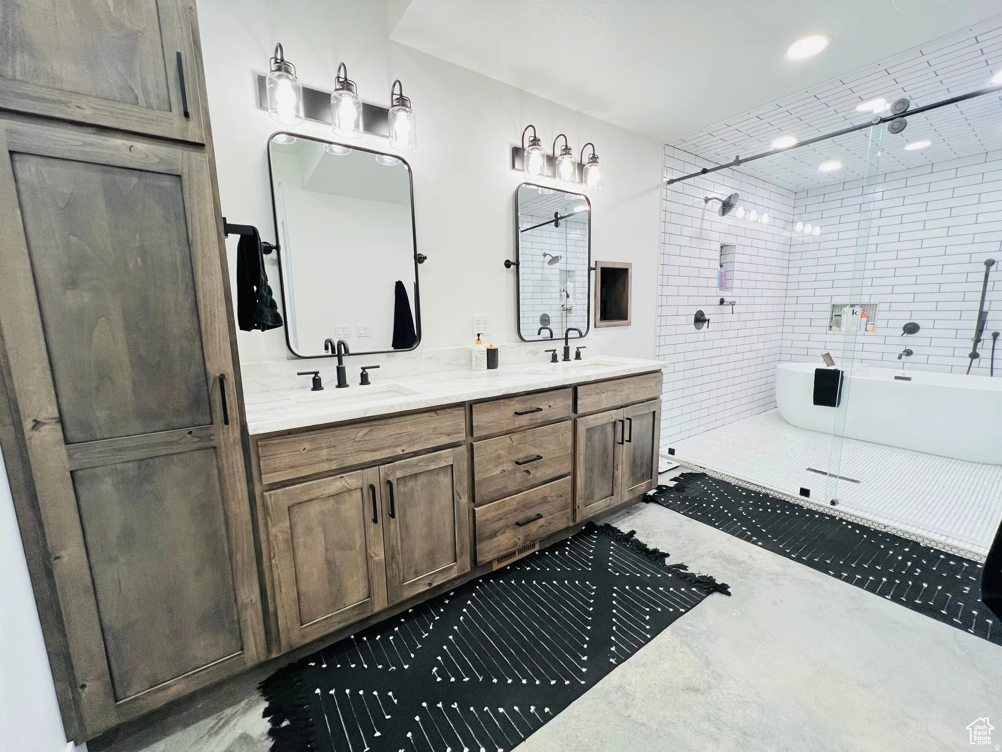 Full bathroom with double vanity, a freestanding tub, concrete flooring, and tiled shower