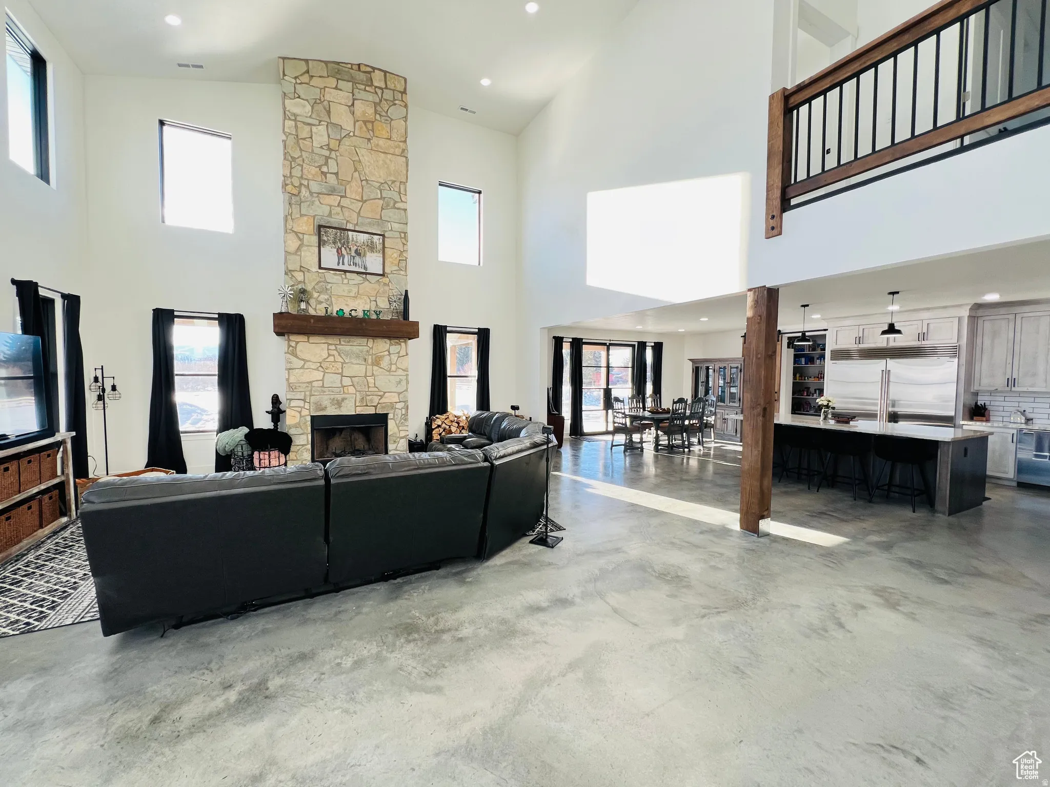 Living area featuring finished concrete floors, a fireplace, plenty of natural light, recessed lighting, and lofted ceiling