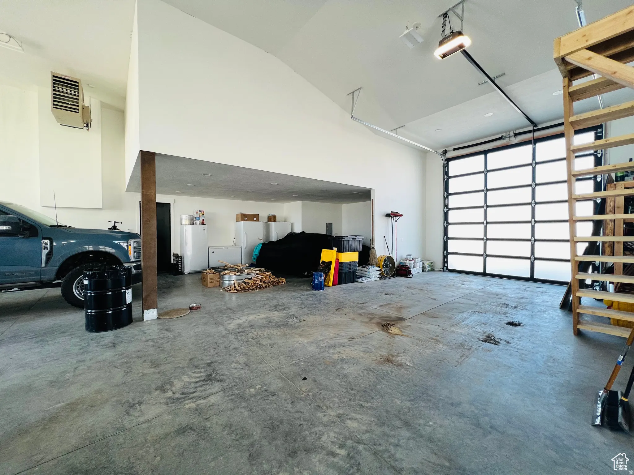 Garage with freestanding refrigerator, white fridge, a heating unit, a garage door opener, and fridge