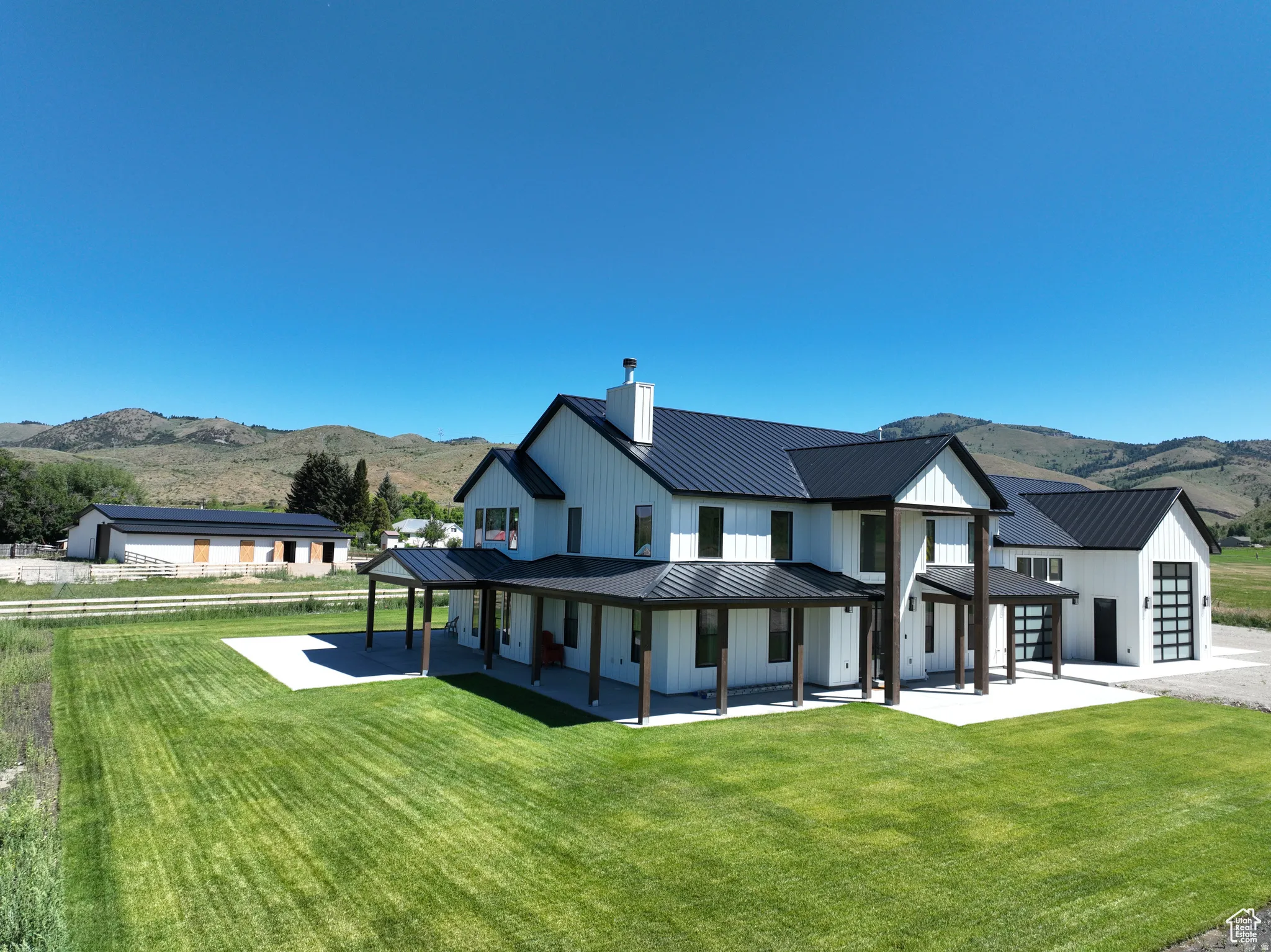Back of property featuring a mountain view, a yard, covered porch, a chimney, and a standing seam roof