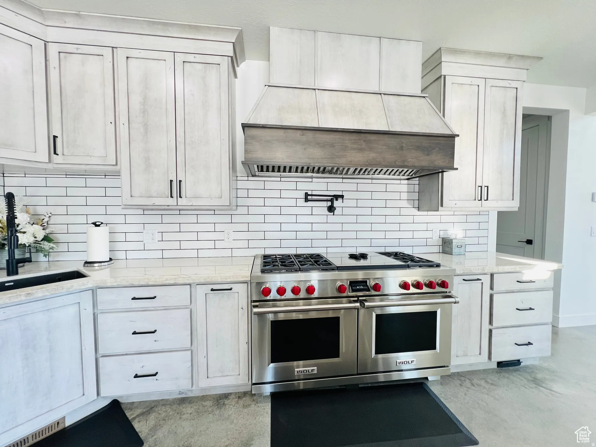 Kitchen featuring range with two ovens, light stone countertops, and backsplash
