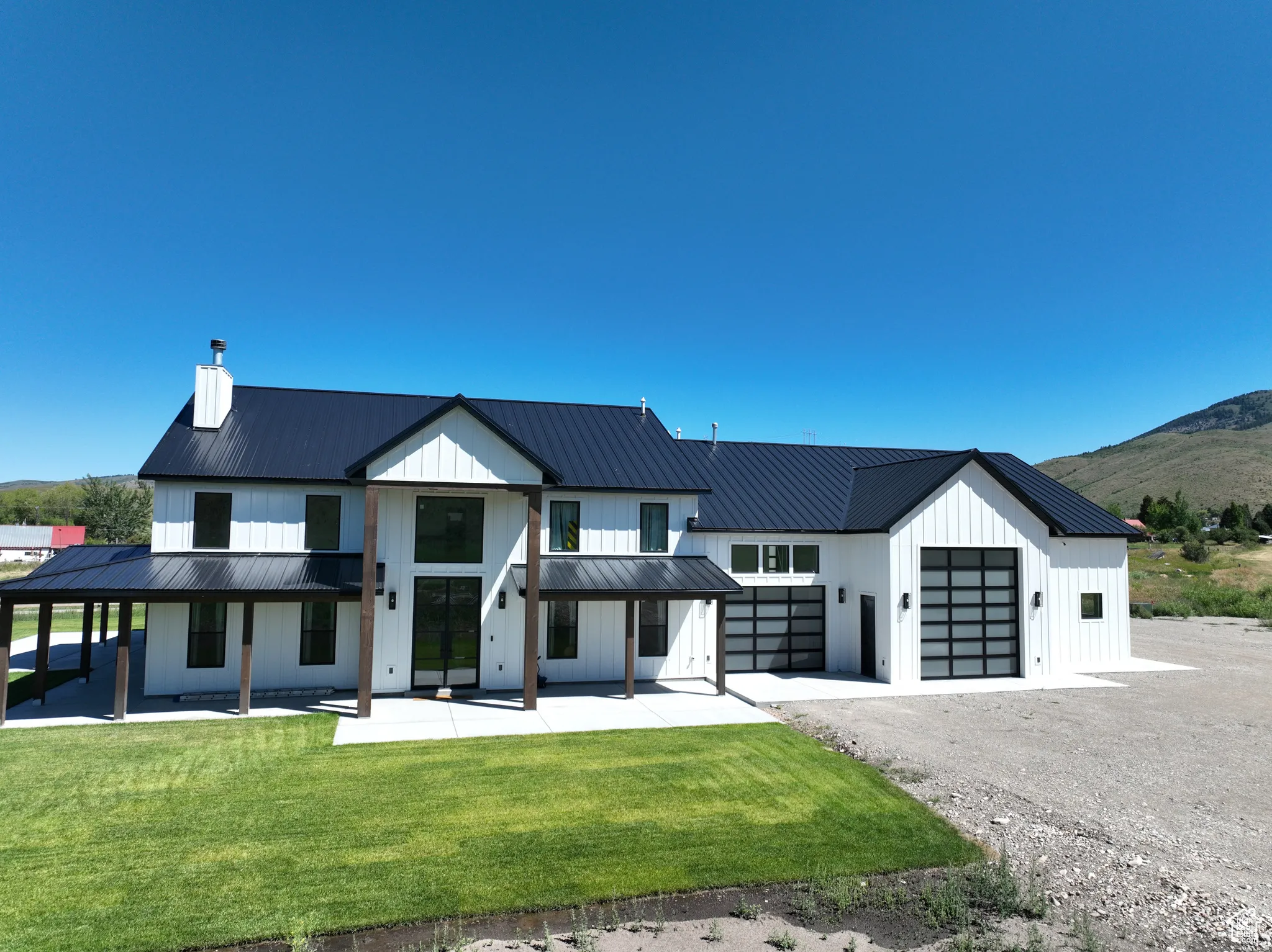 Modern inspired farmhouse with board and batten siding, driveway, a front yard, a standing seam roof, and a porch