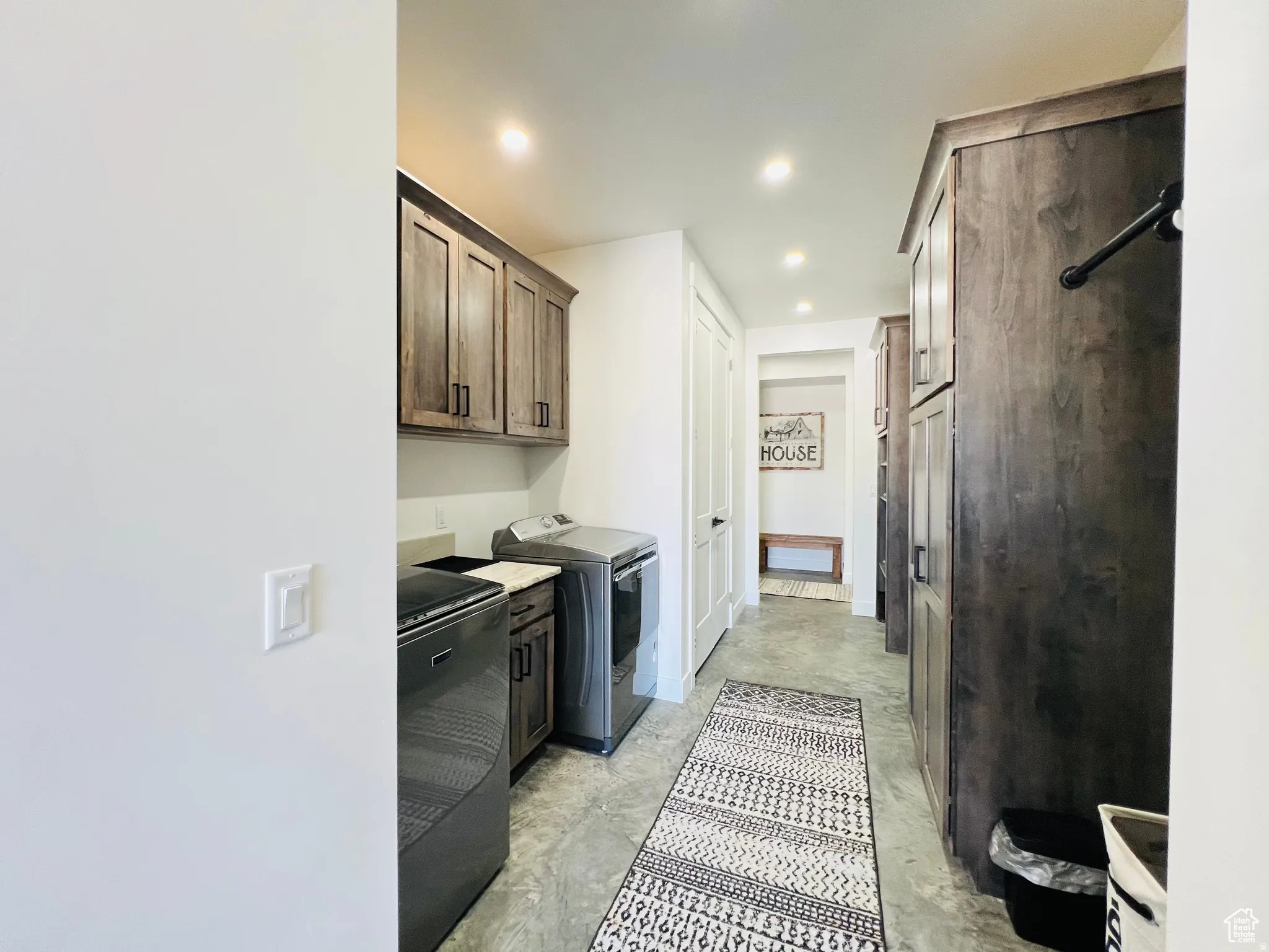Laundry area featuring unfinished concrete flooring, washer and dryer, recessed lighting, and cabinet space