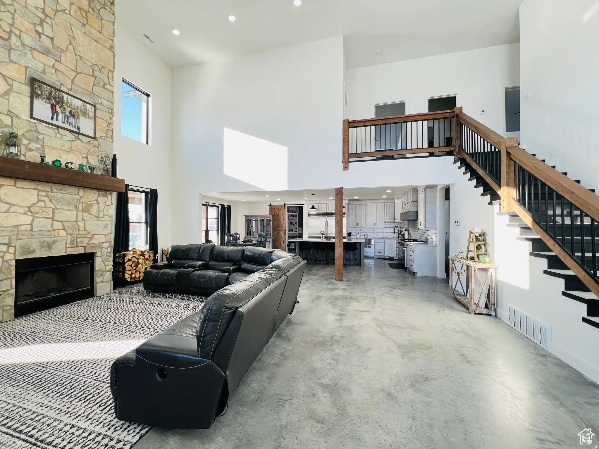 Living area featuring recessed lighting, concrete flooring, a high ceiling, and a fireplace