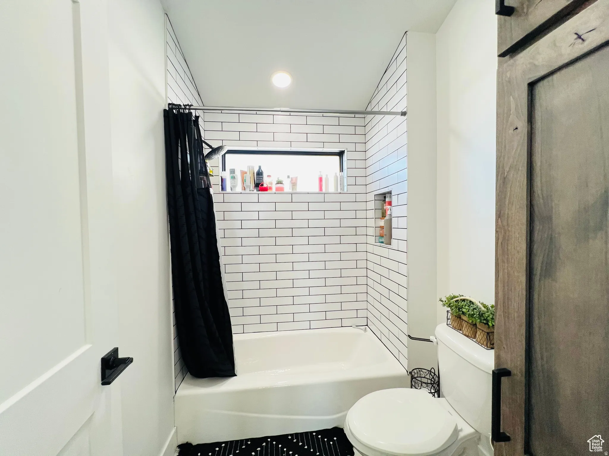Bathroom featuring toilet and shower / bath combo with shower curtain