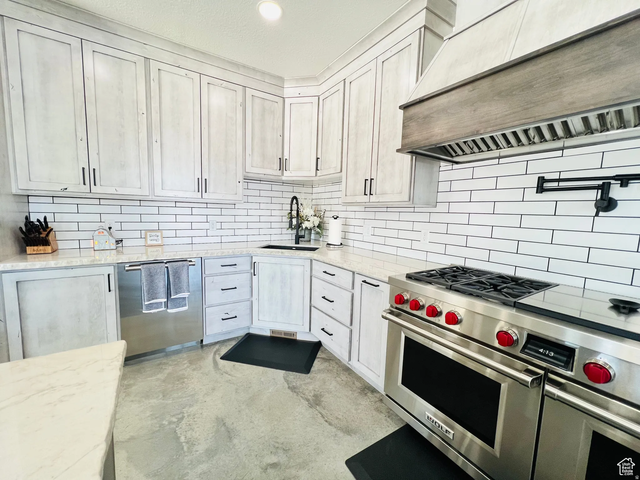 Kitchen with stainless steel appliances, light stone countertops, concrete flooring, recessed lighting, and backsplash