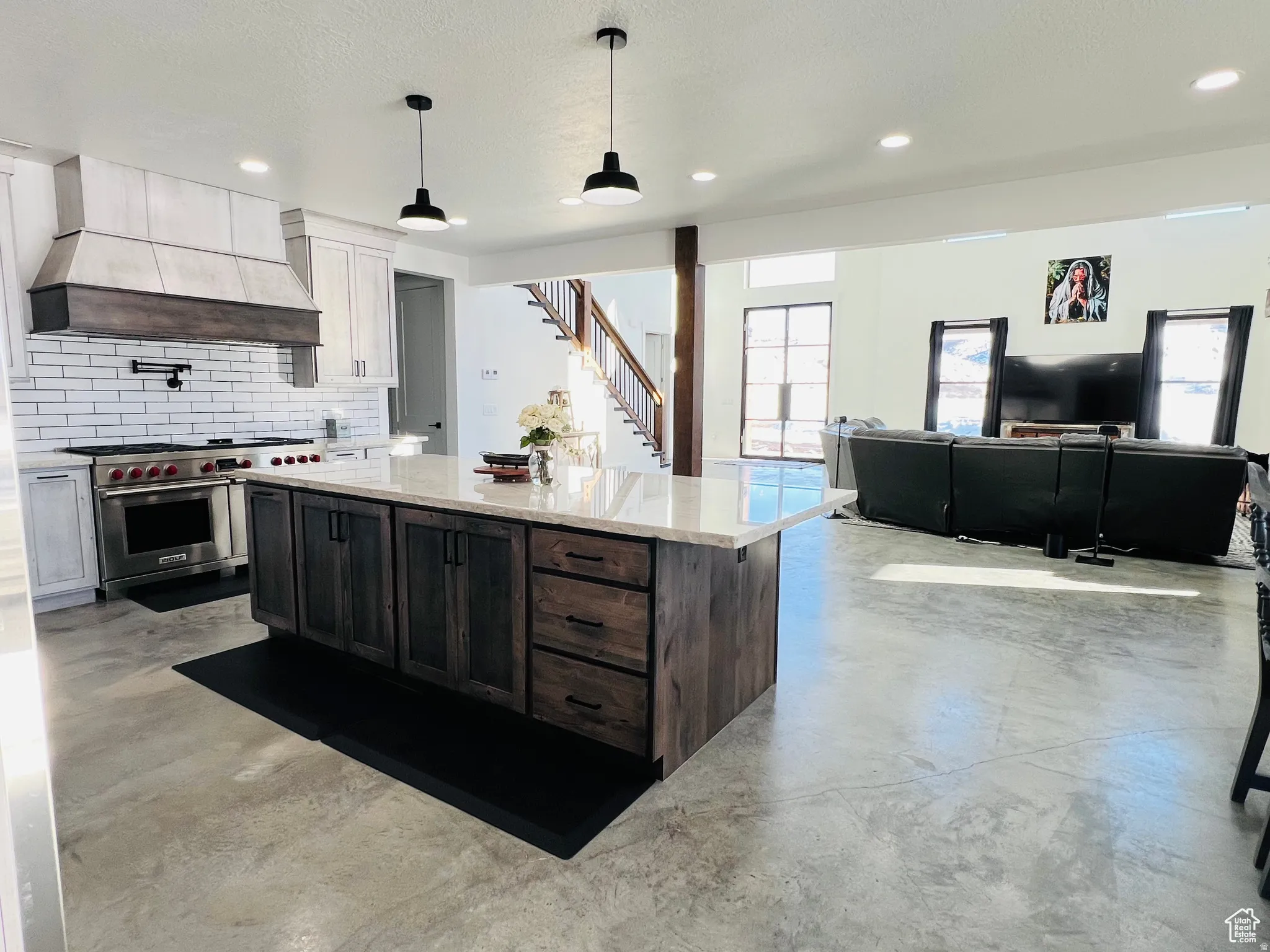 Kitchen featuring finished concrete flooring, light stone countertops, double oven range, a center island, and open floor plan