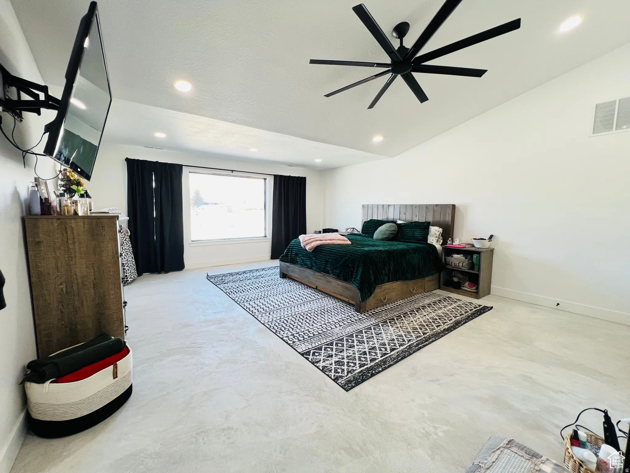 Bedroom featuring ceiling fan, concrete flooring, and lofted ceiling
