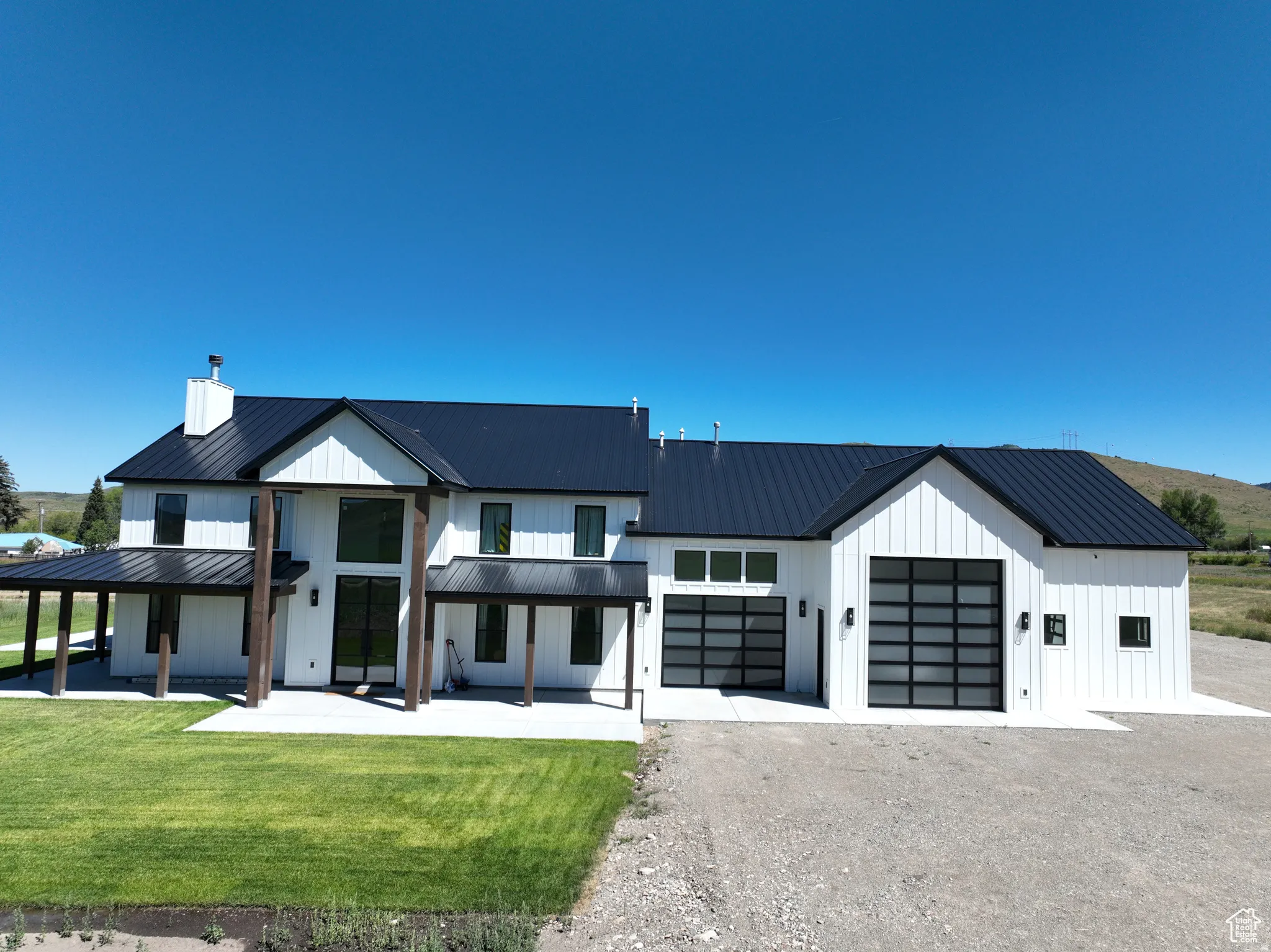 Modern farmhouse style home with driveway, a front yard, board and batten siding, and a porch