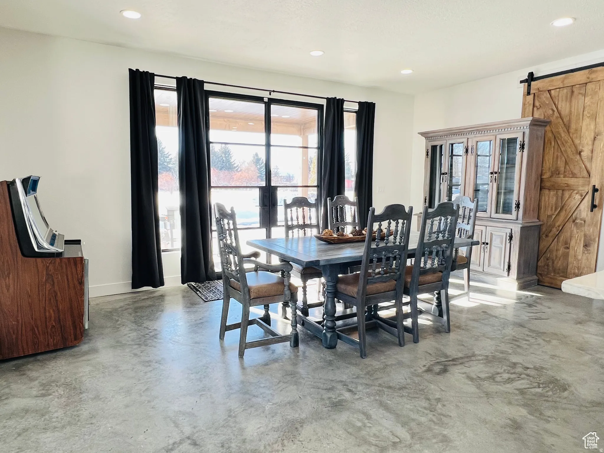 Dining area featuring a barn door, concrete flooring, and recessed lighting