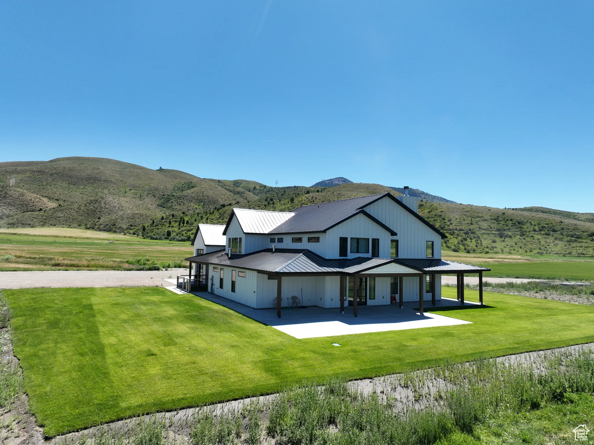 Rear view of property with a metal roof, a mountain view, a yard, and a patio area