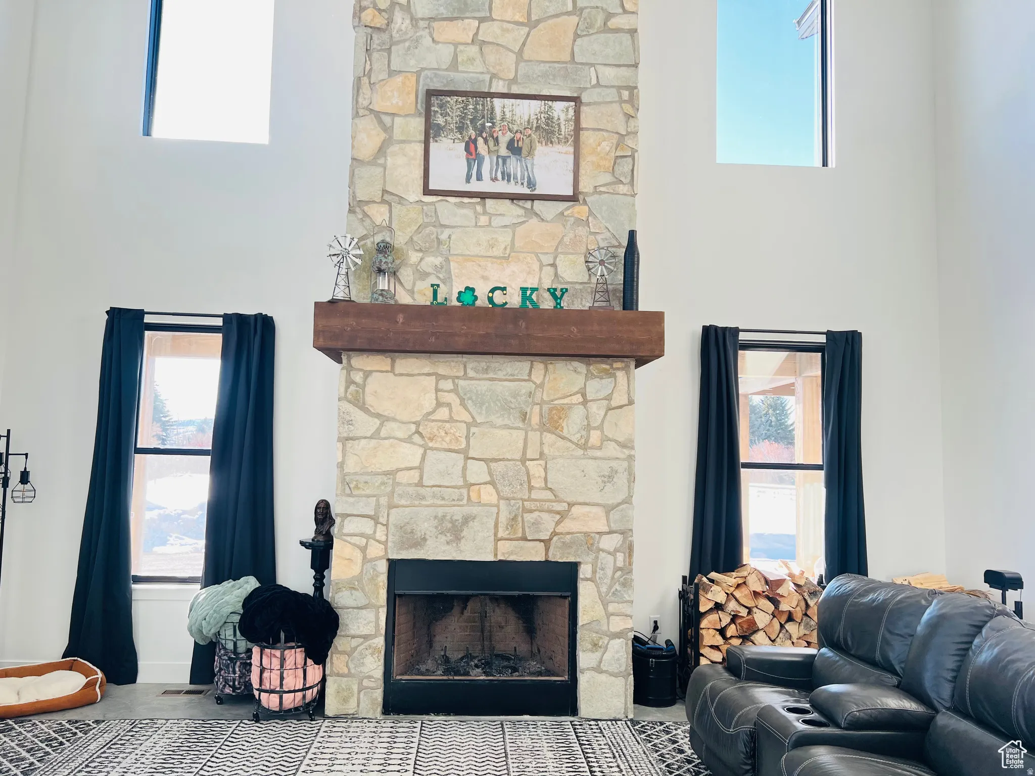 Living room featuring a stone fireplace and a high ceiling