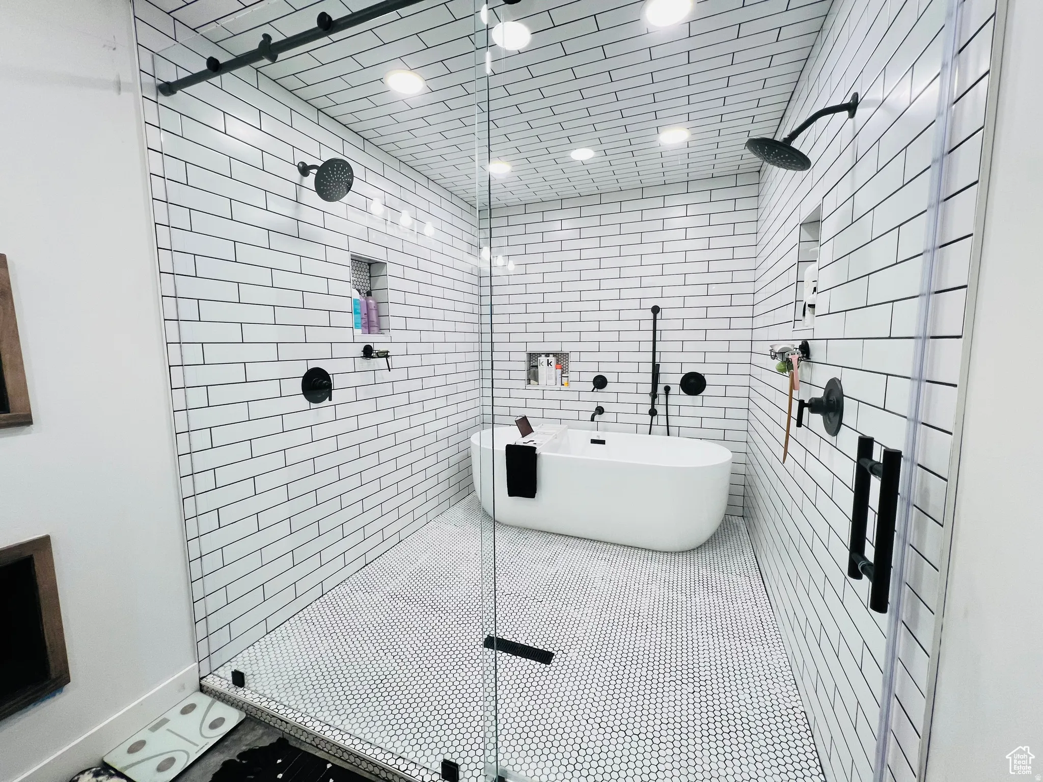 Full bathroom with a stall shower, a freestanding bath, and tile walls