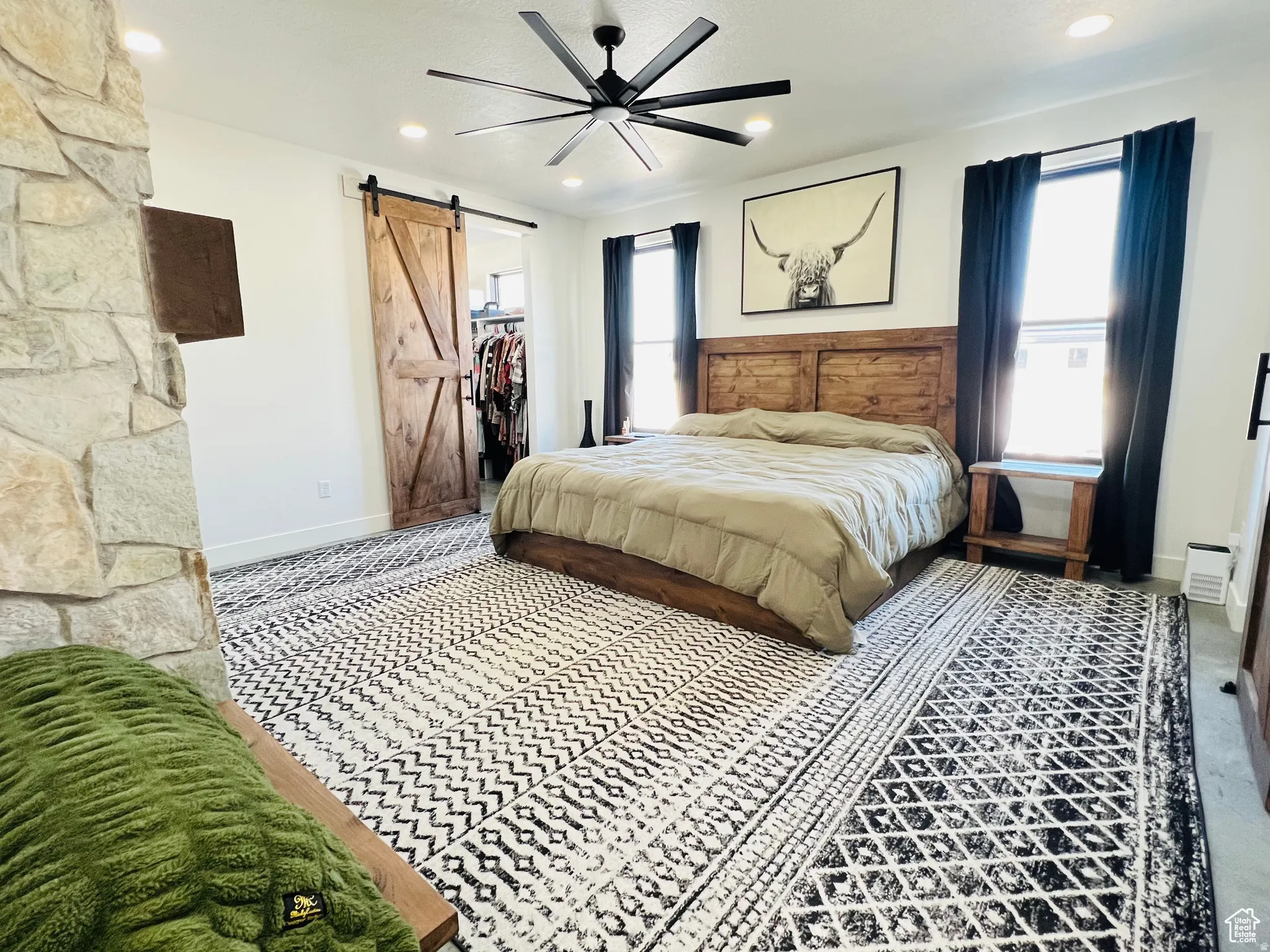 Bedroom featuring a barn door, ceiling fan, a walk in closet, and recessed lighting