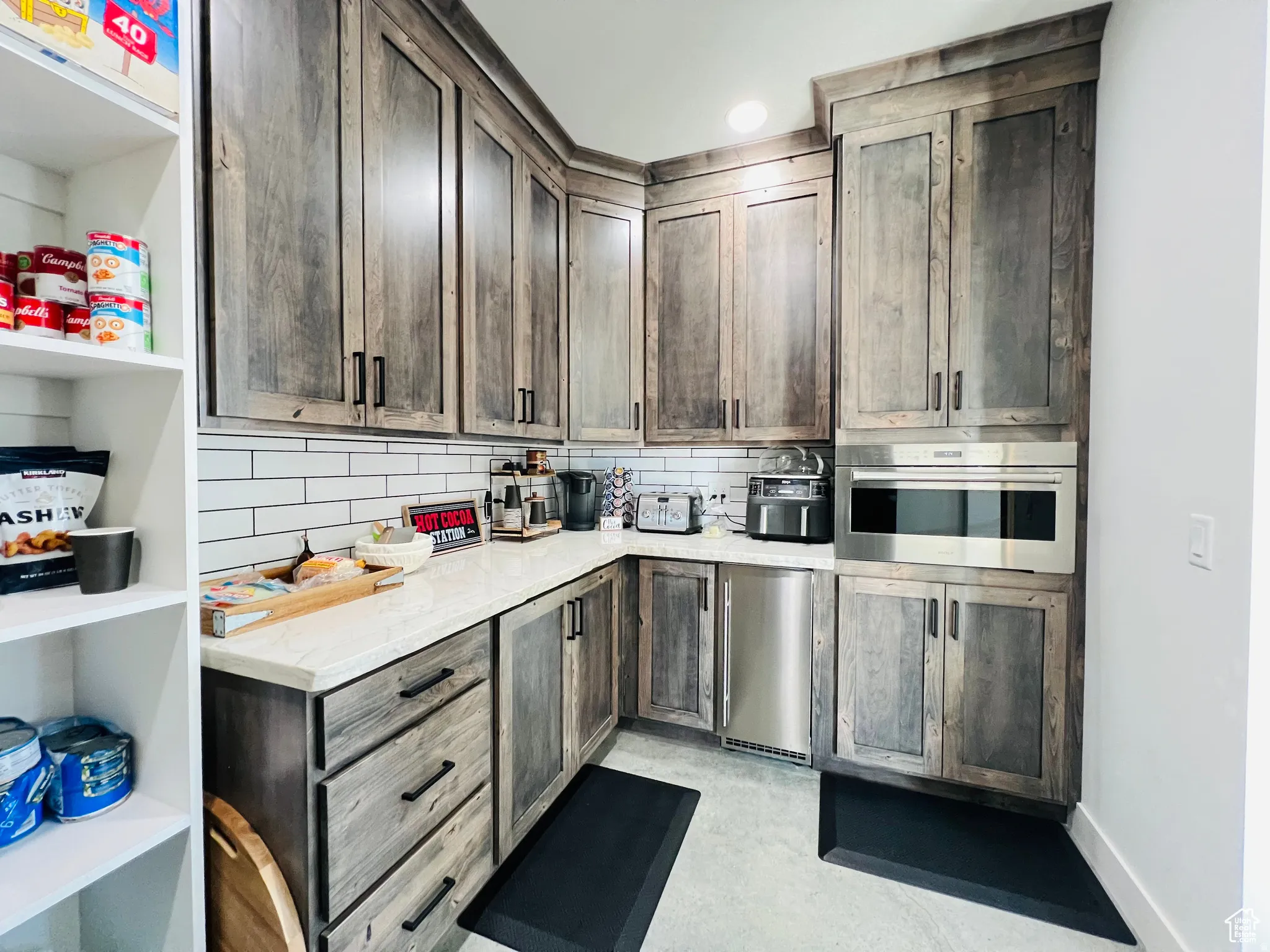 Kitchen featuring dark wood finish cabinetry, tasteful backsplash, stainless steel appliances, and light stone countertops