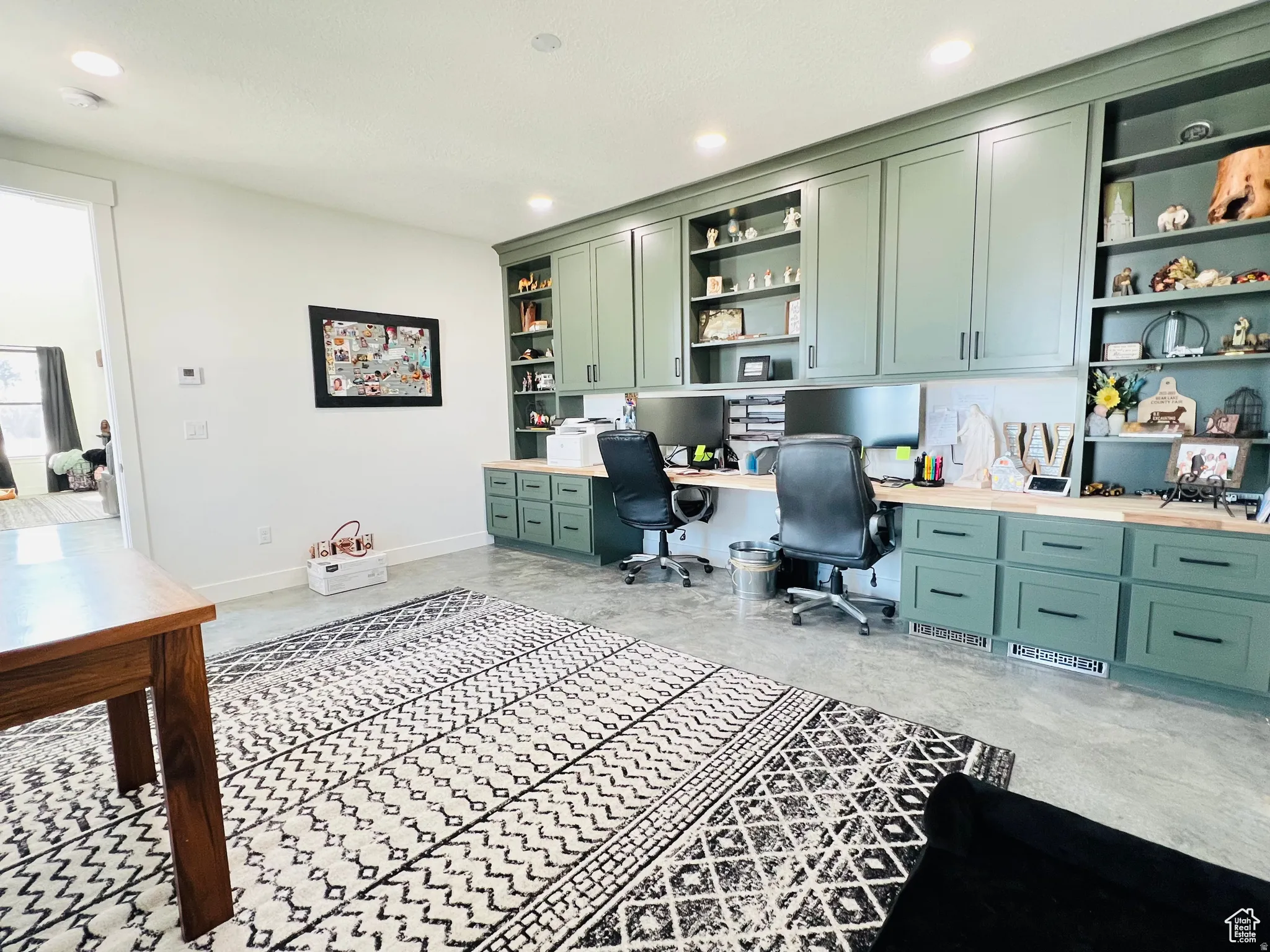 Home office with built in study area, built in features, recessed lighting, and concrete floors